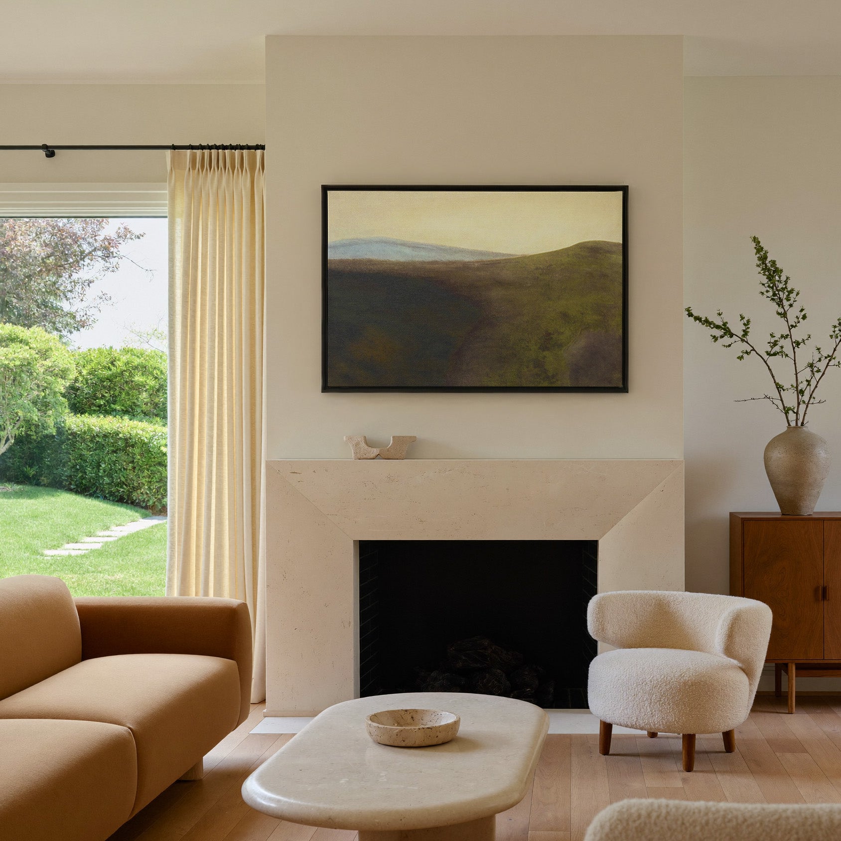 muted green hills with a pale blue ridge and canvas wall art in a black frame above a mantel