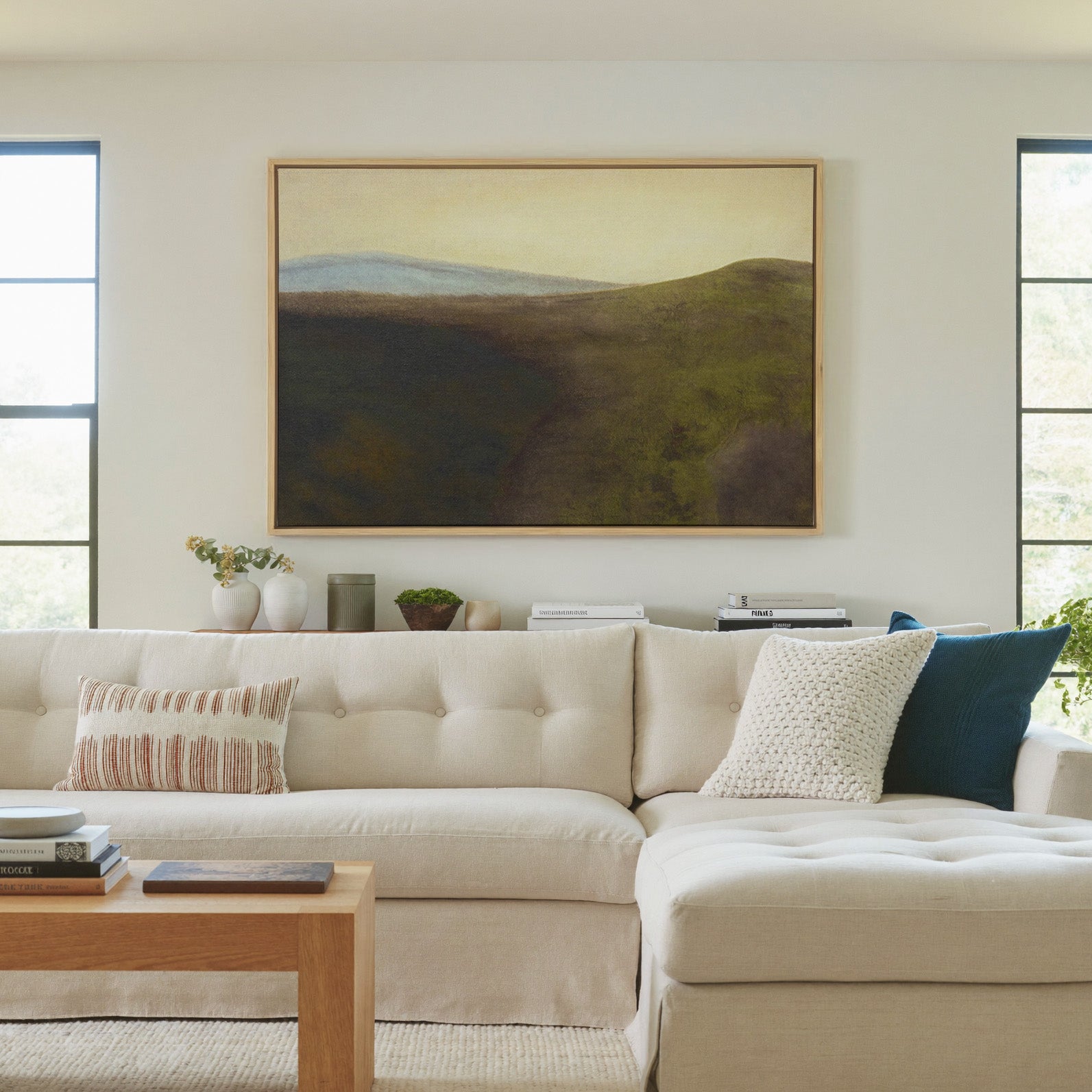 muted green hills with a pale blue ridge and canvas wall art in a natural wood frame in a living room