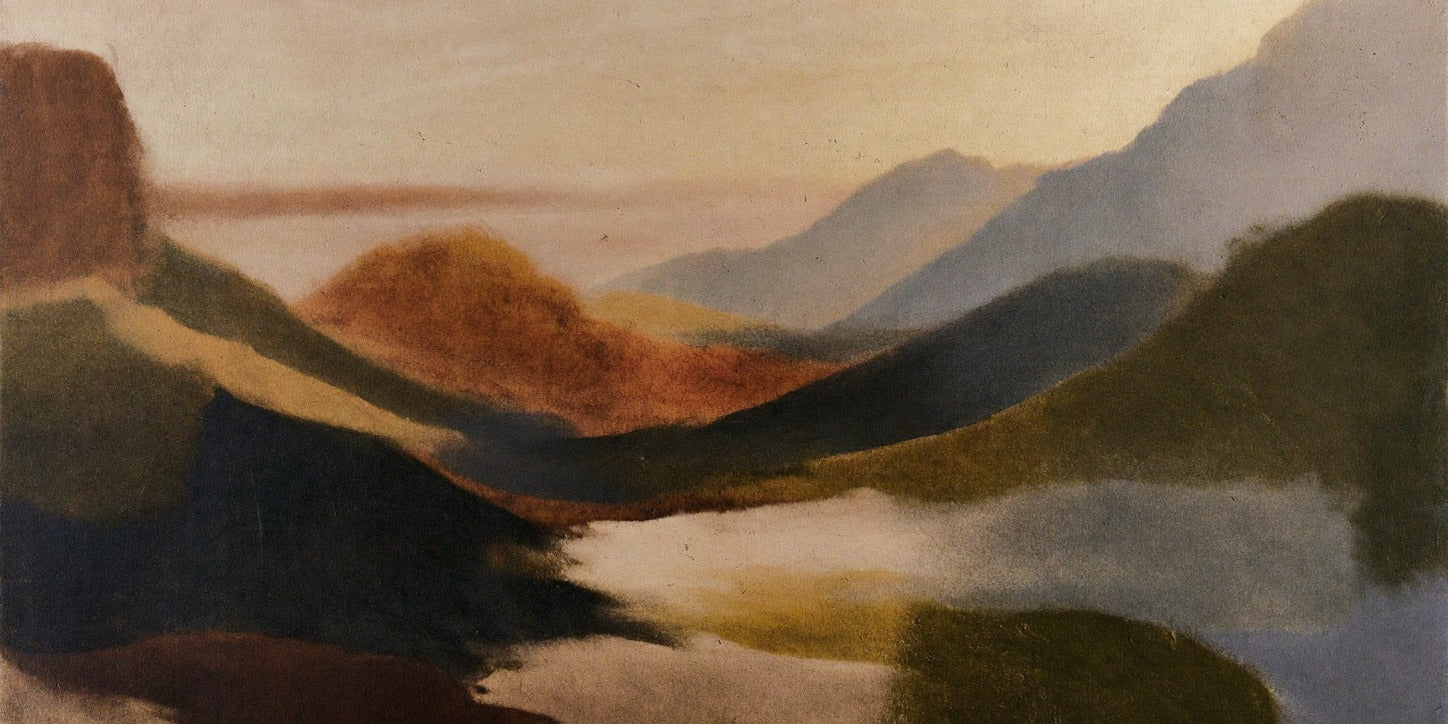 Layered headlands, pale water, and a warm cream sky in a wide coastal landscape