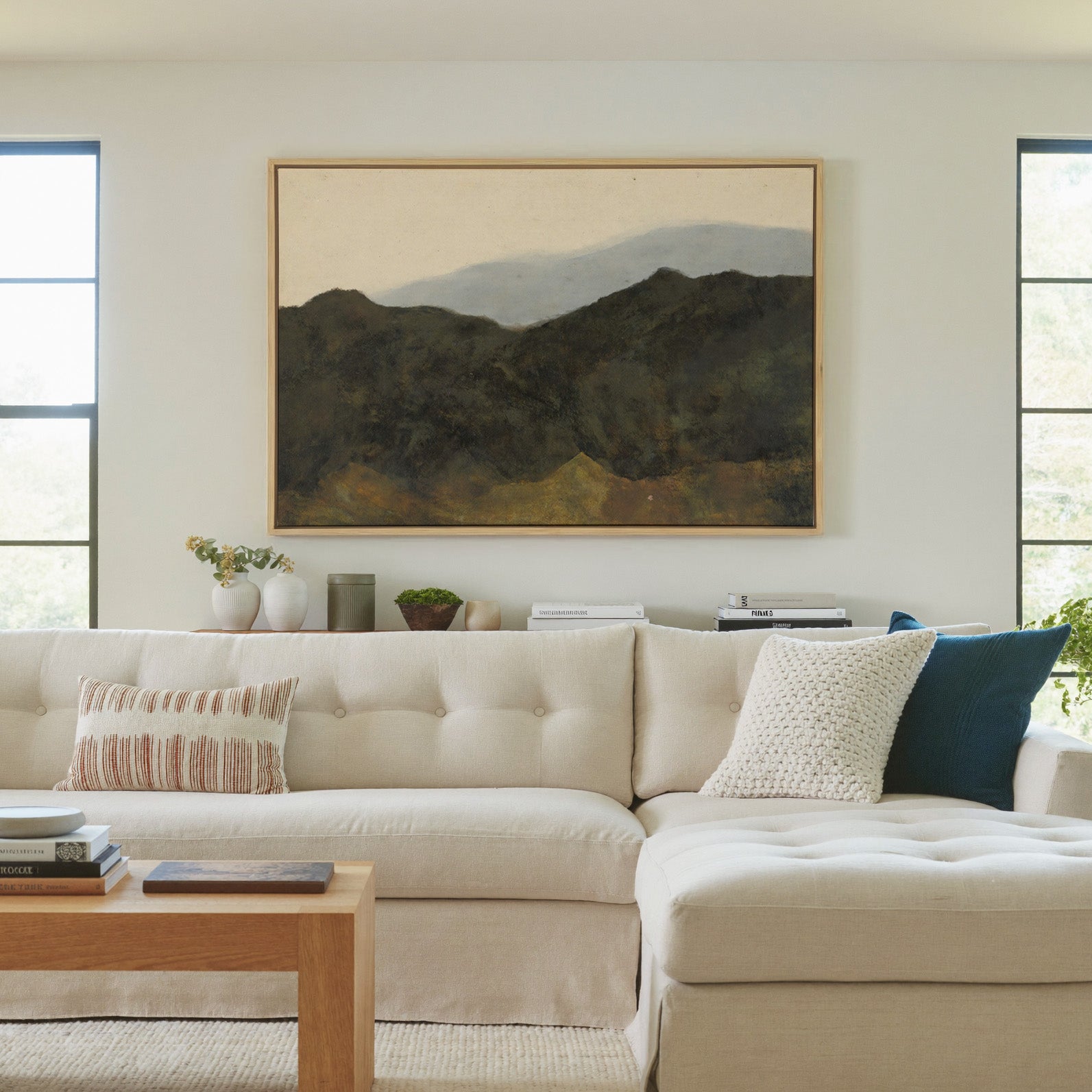 dark mountain ridges beneath a pale hazy sky canvas wall art in a natural wood frame in a living room