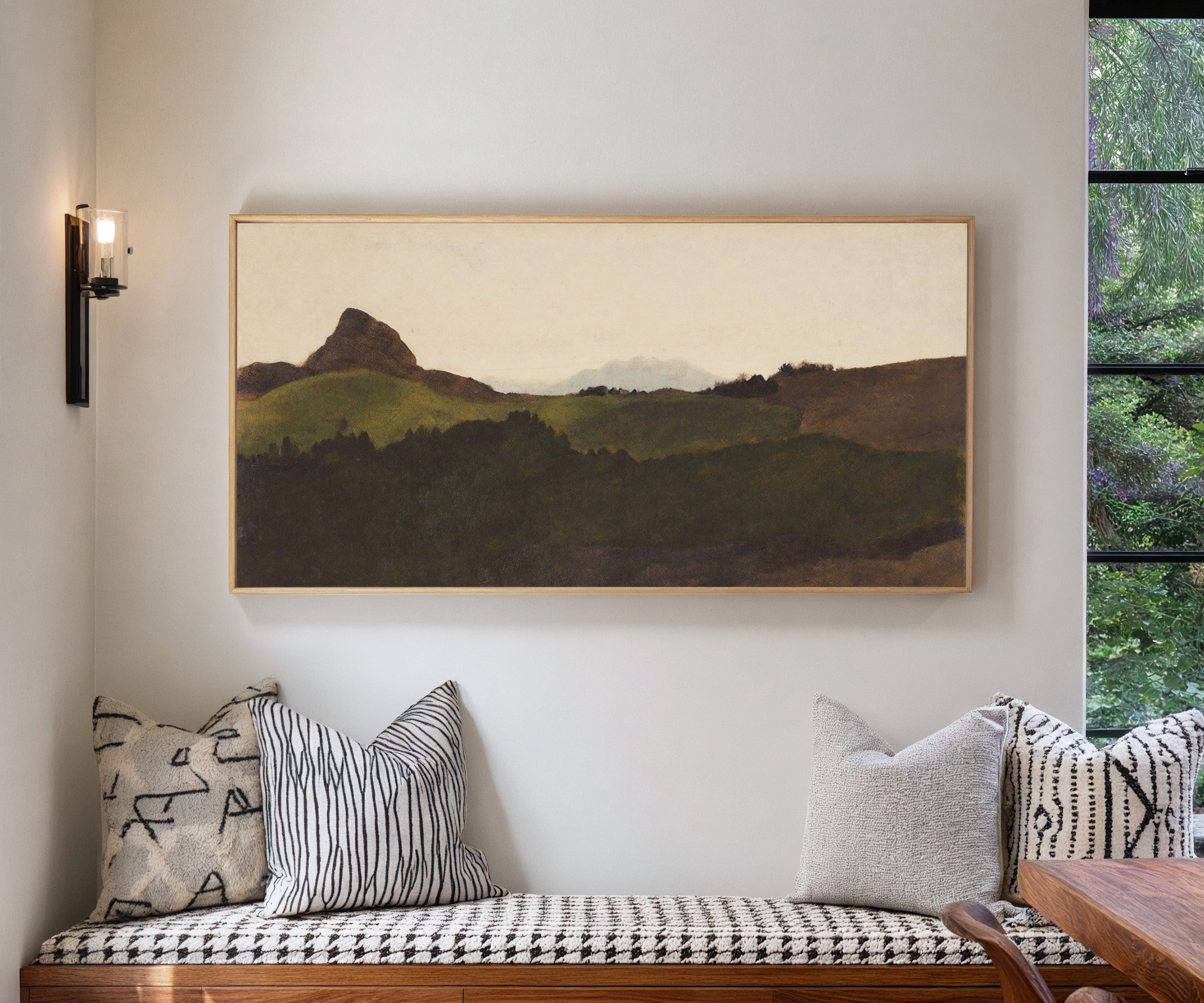 dark green hills with a pale distant peak canvas wall art in a natural wood frame in a living room