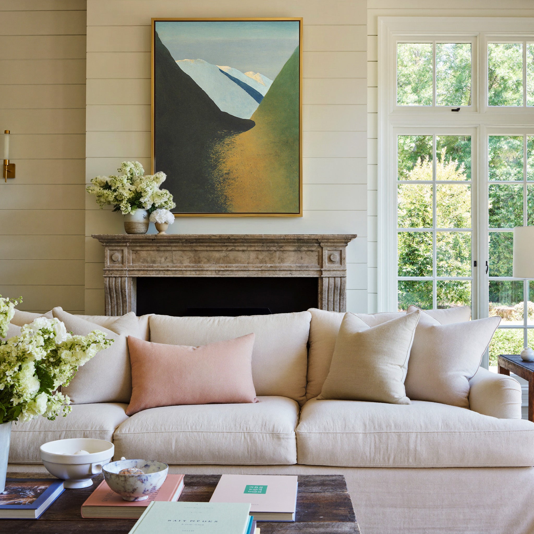 dark foreground slopes with pale blue peaks and canvas wall art in a gold frame above a mantel