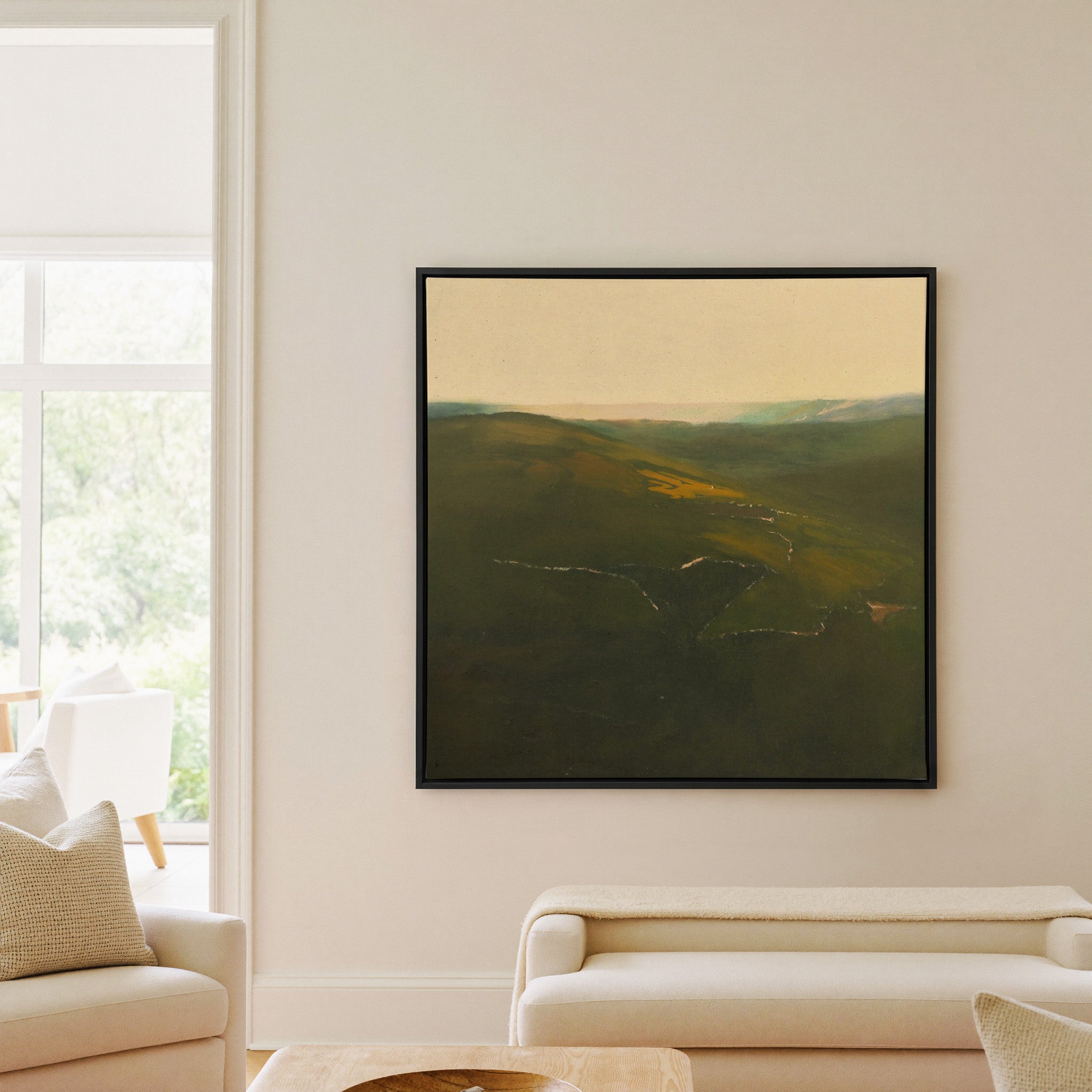 green valley landscape with a winding river and canvas wall art in a black frame in a living room