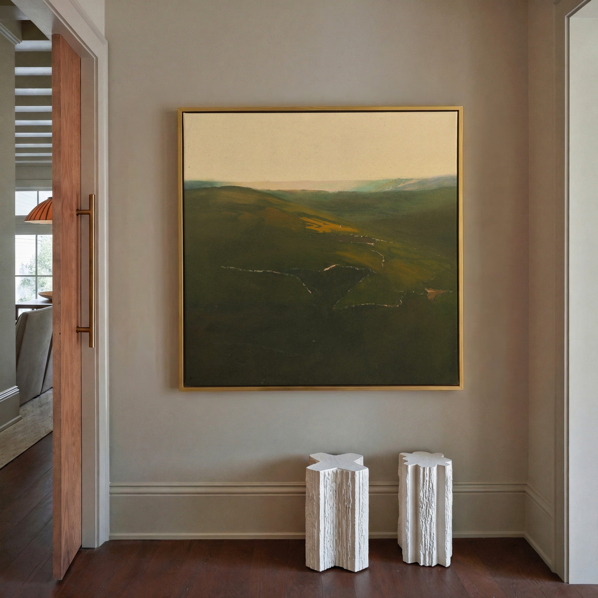 green valley landscape with a winding river and canvas wall art in a gold frame in a styled room setting