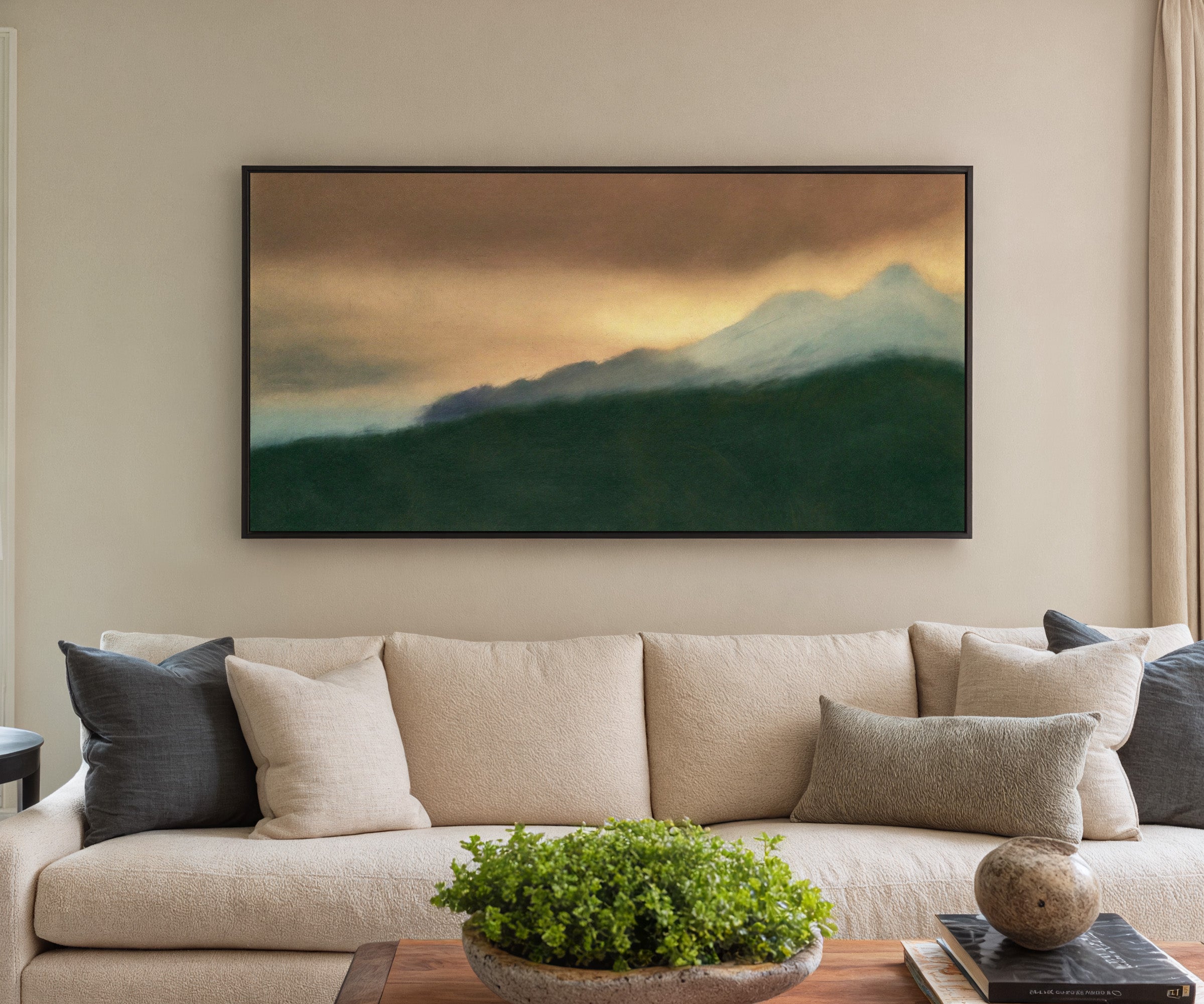 dark green foreground with pale blue peaks and canvas wall art in a black frame in a styled room setting