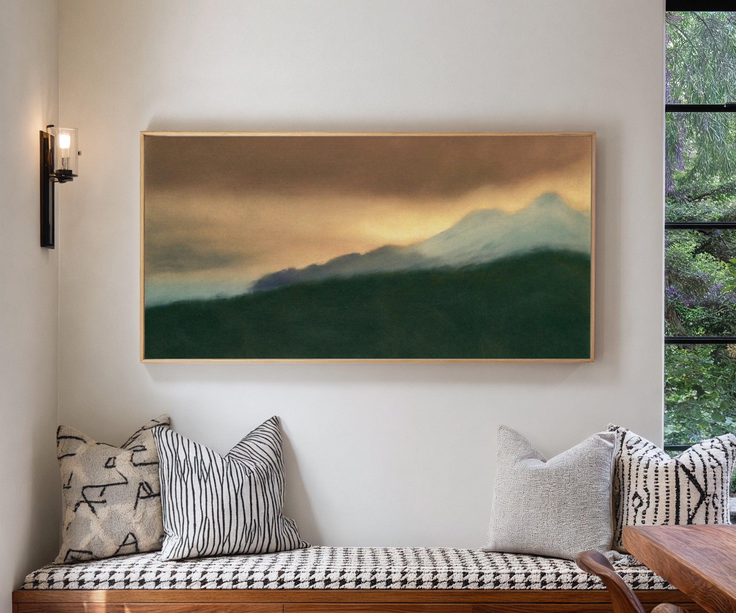 dark green foreground with pale blue peaks and canvas wall art in a natural wood frame in a living room