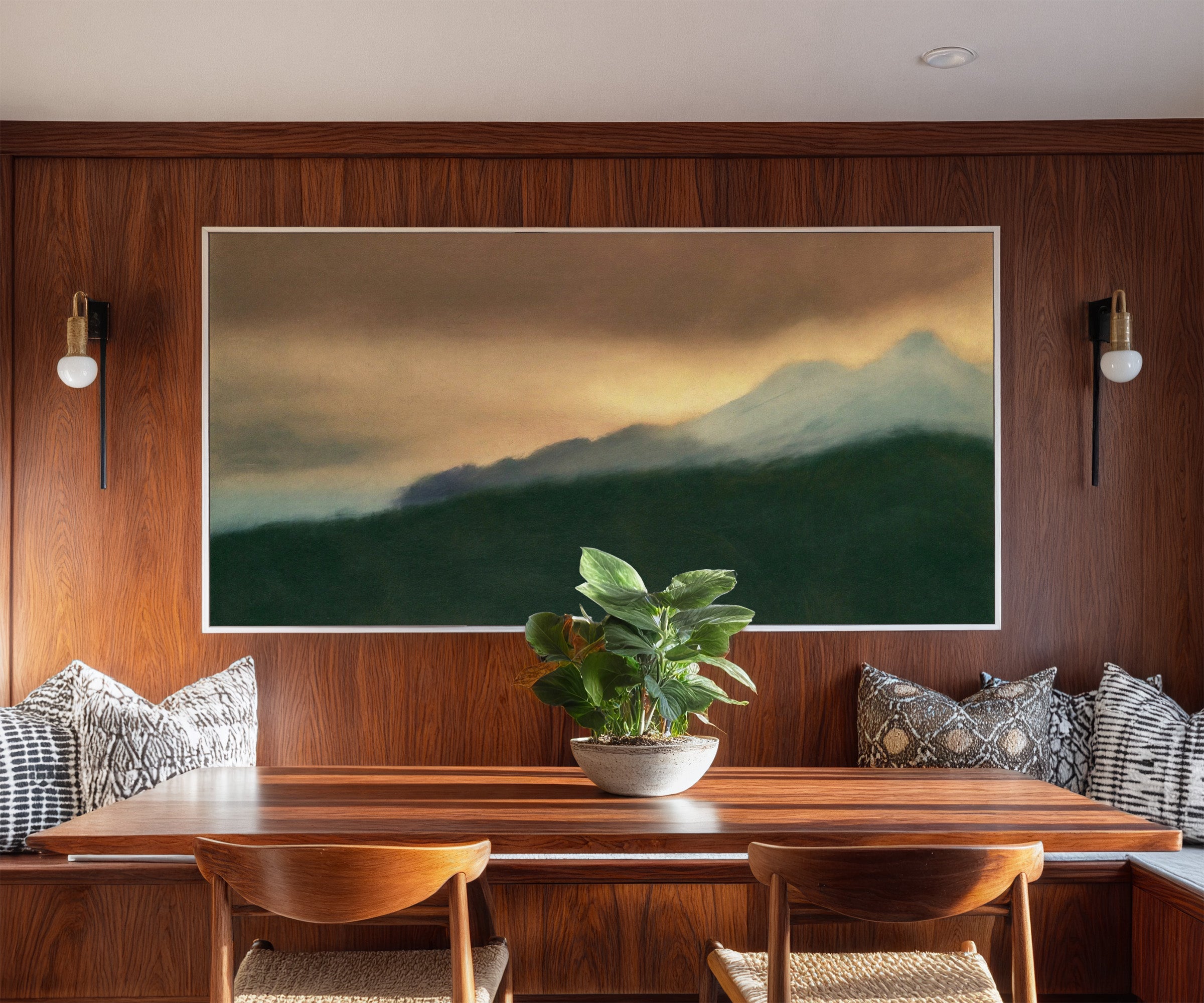 dark green foreground with pale blue peaks and canvas wall art in a white frame in a styled room setting