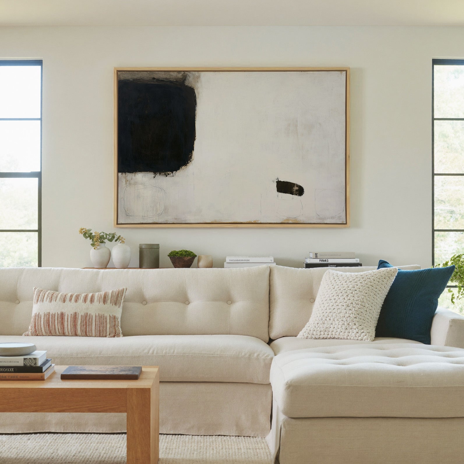 sparse black and cream abstract with heavy dark canvas wall art in a natural wood frame in a living room