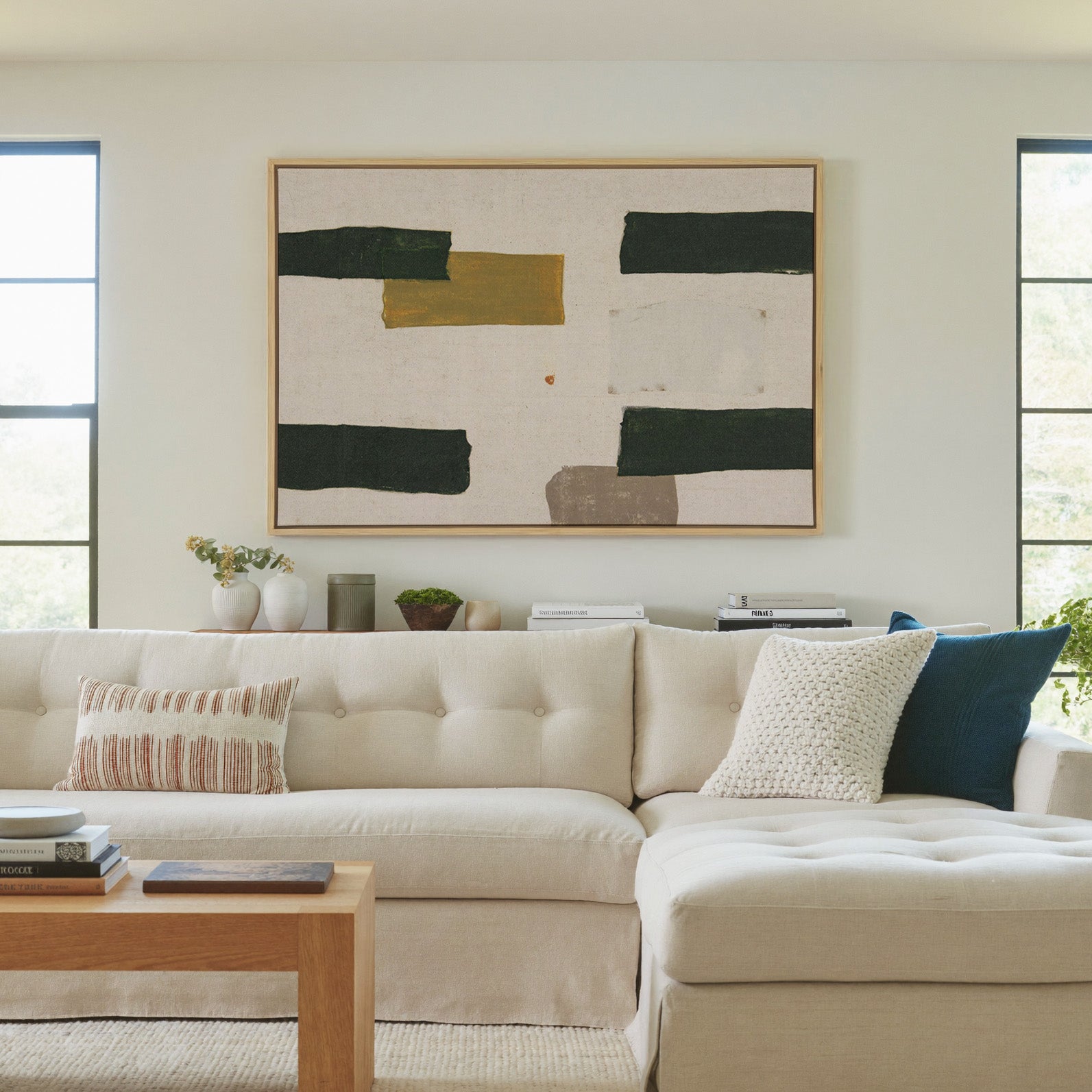 cream abstract with dark green blocks and a canvas wall art in a natural wood frame in a living room