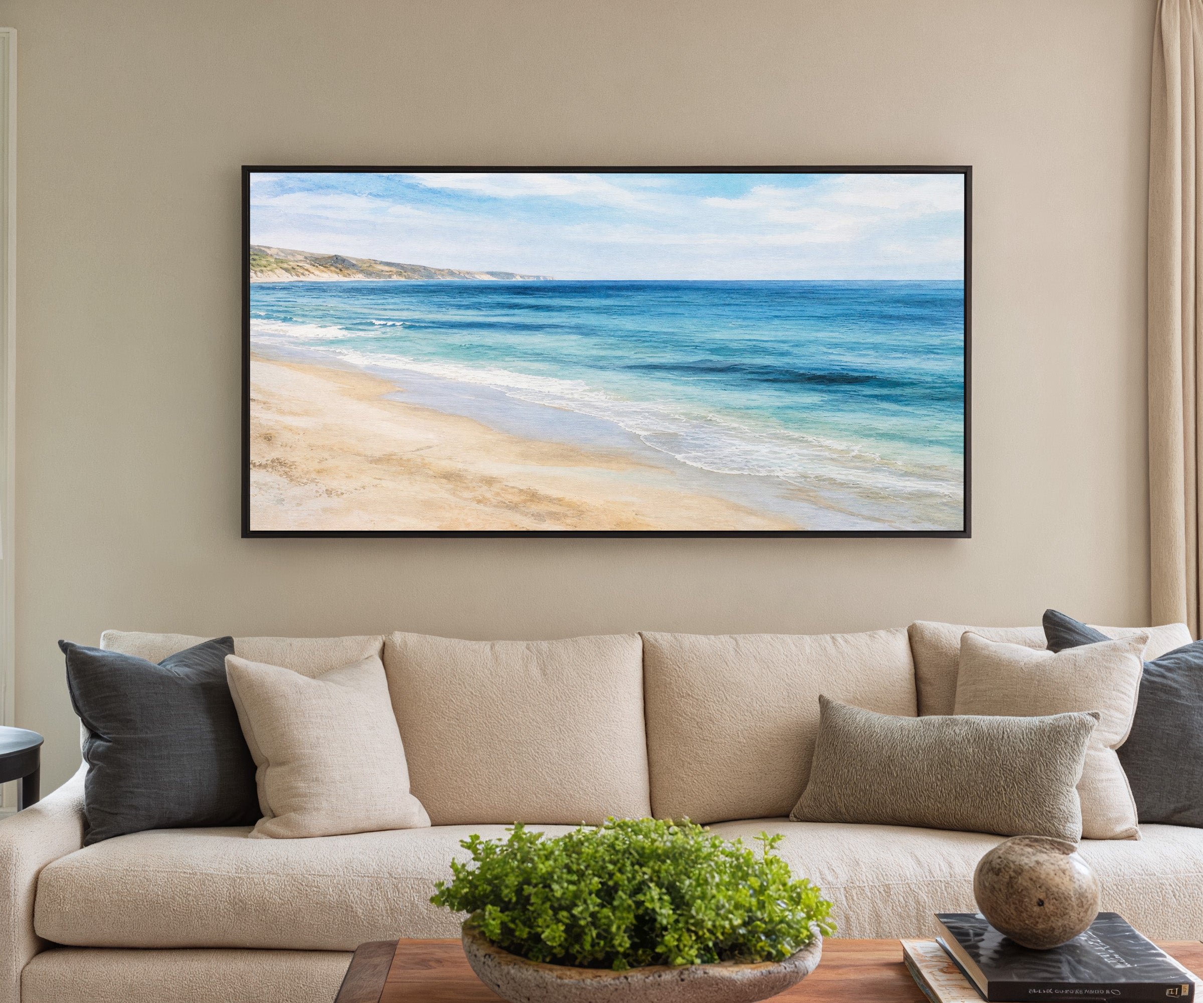 blue sea with pale sand and distant headland canvas wall art in a black frame in a styled room setting