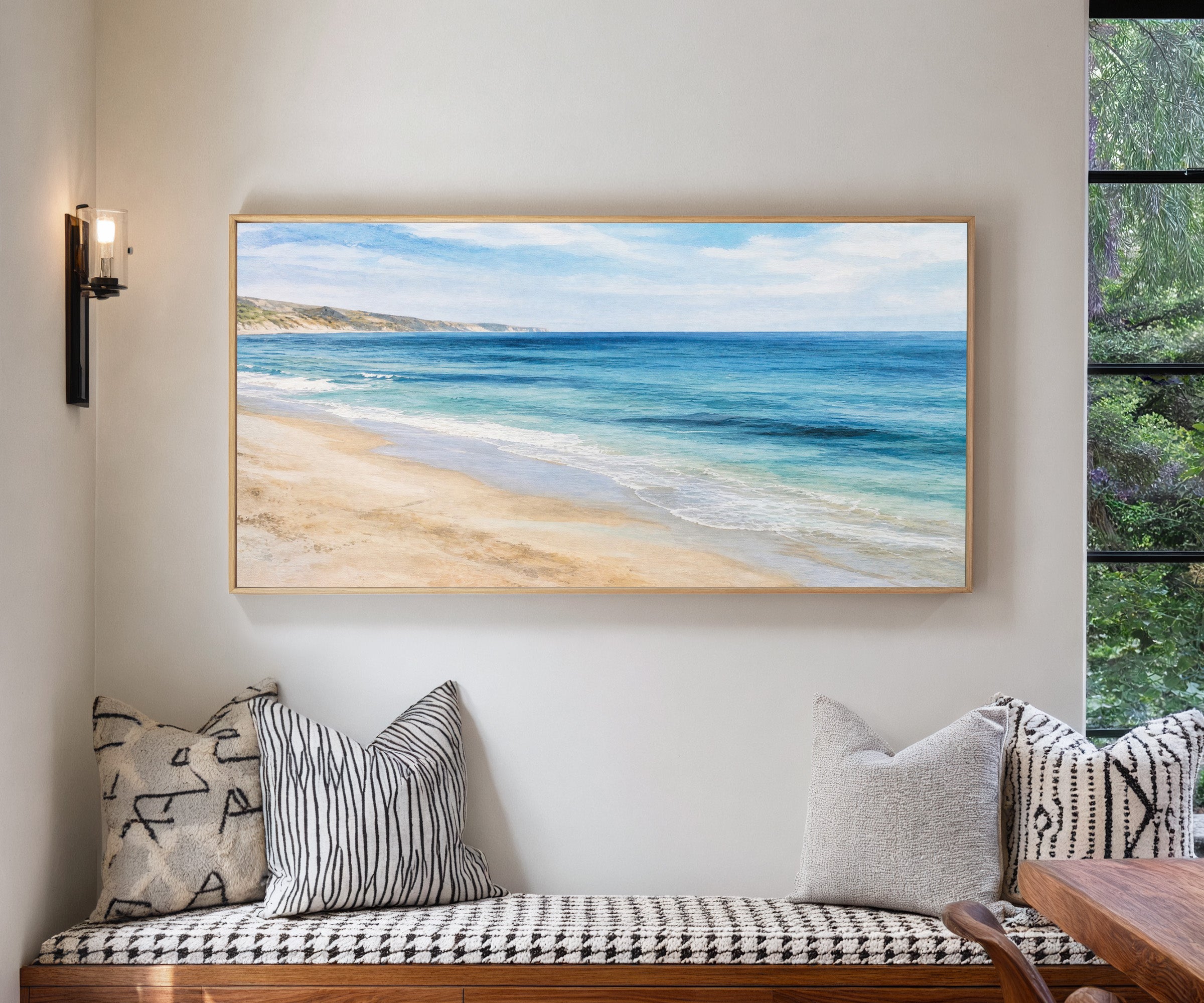 blue sea with pale sand and distant headland canvas wall art in a natural wood frame in a living room