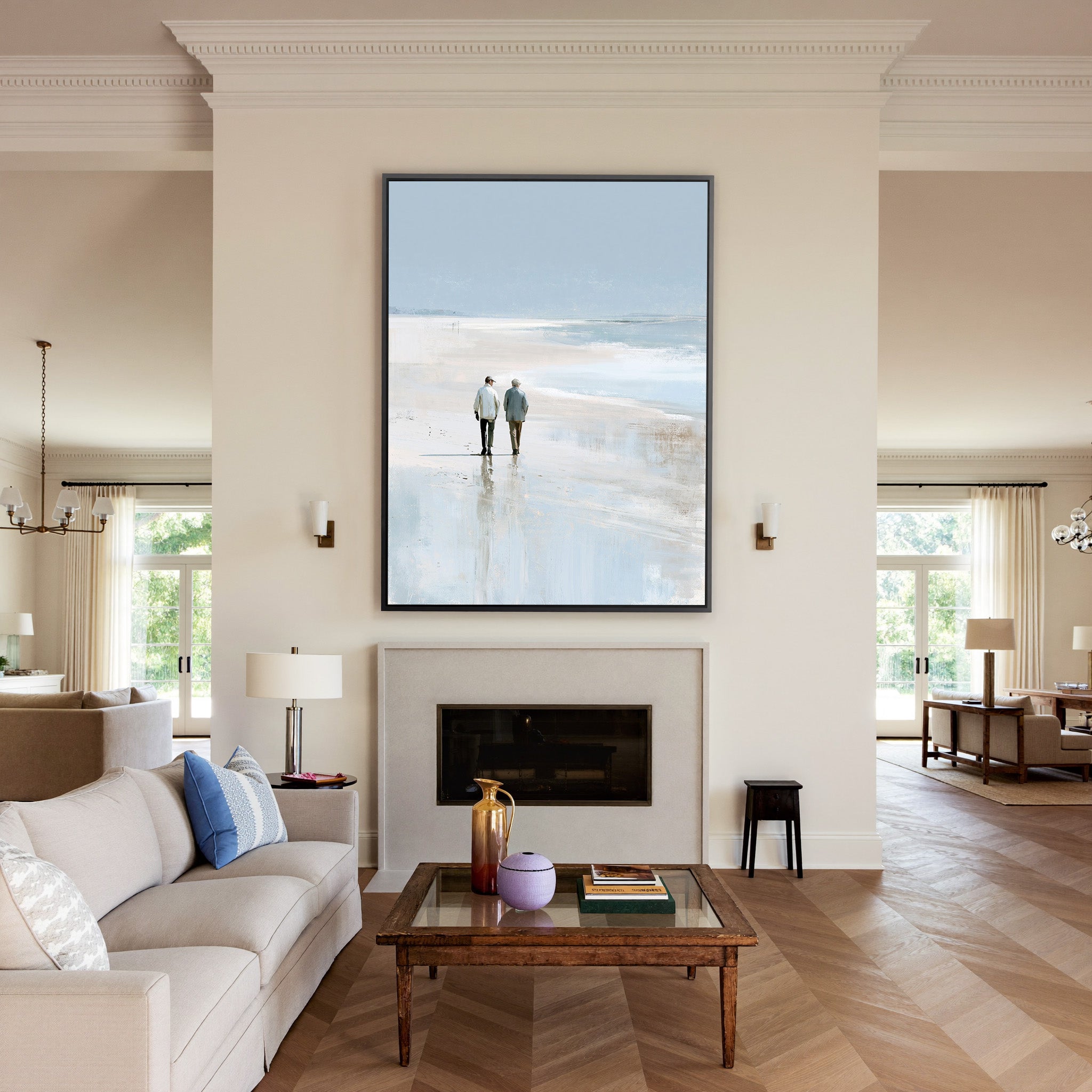 pale beach with two figures and soft blue water canvas wall art in a black frame above a mantel