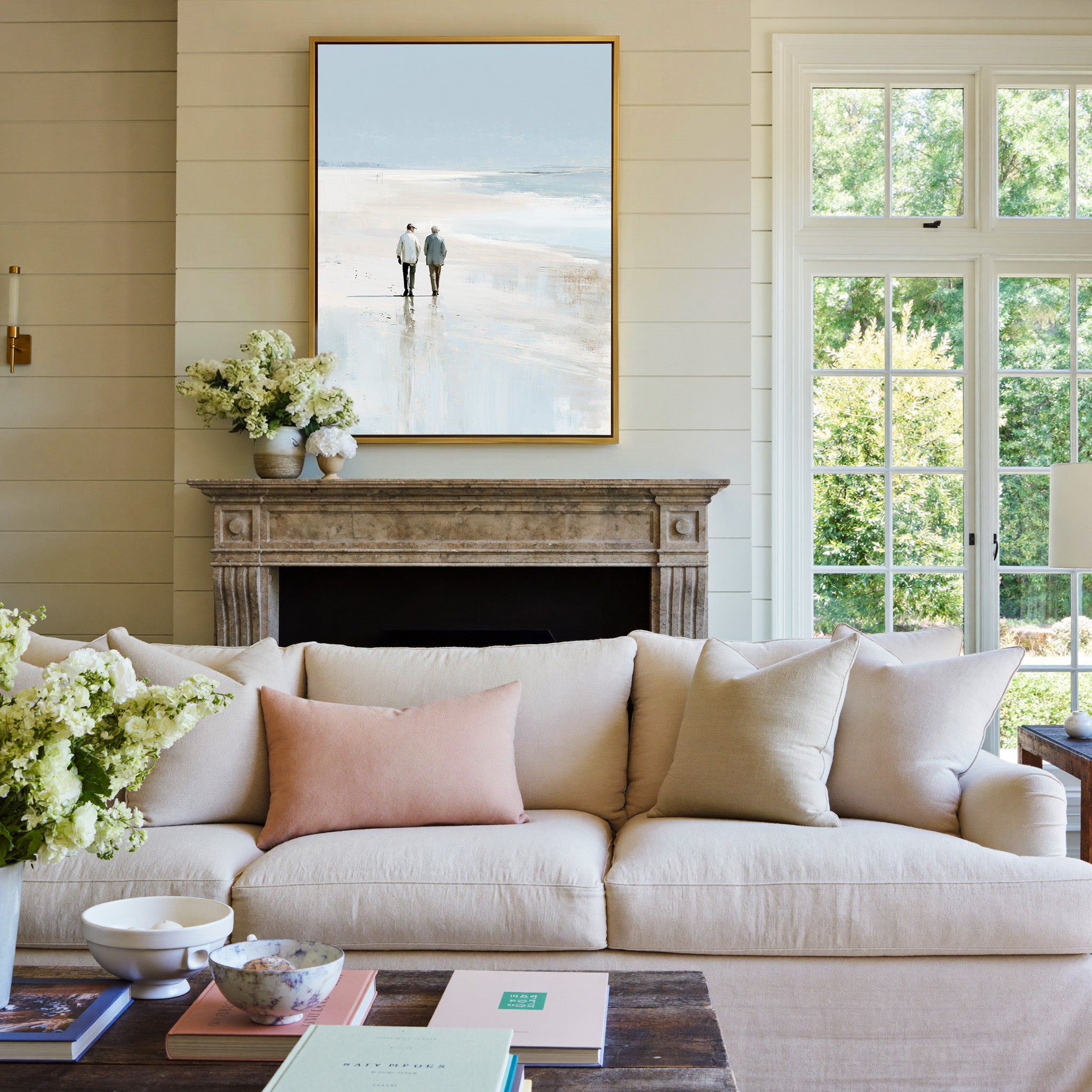 pale beach with two figures and soft blue water canvas wall art in a gold frame above a mantel