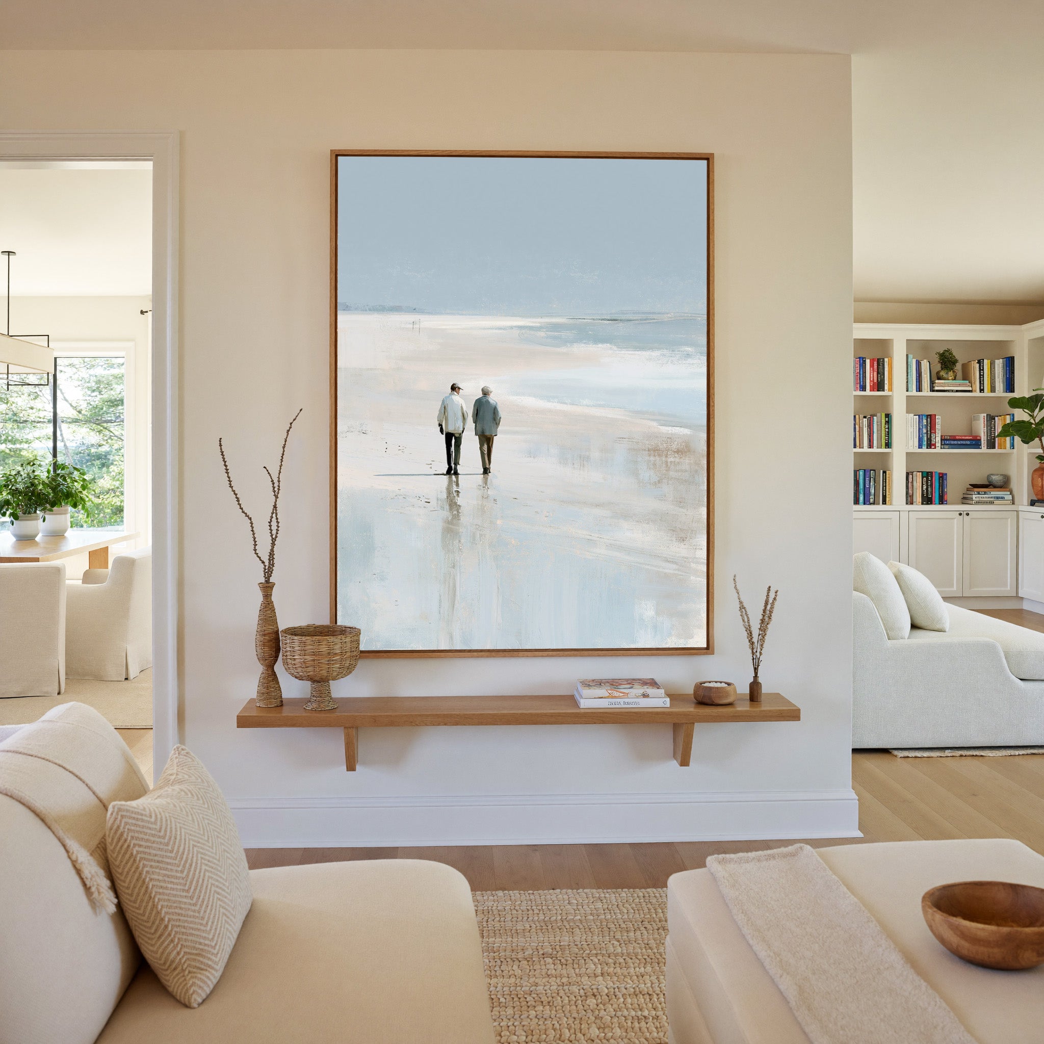 pale beach with two figures and soft blue water canvas wall art in an oak frame in a living room