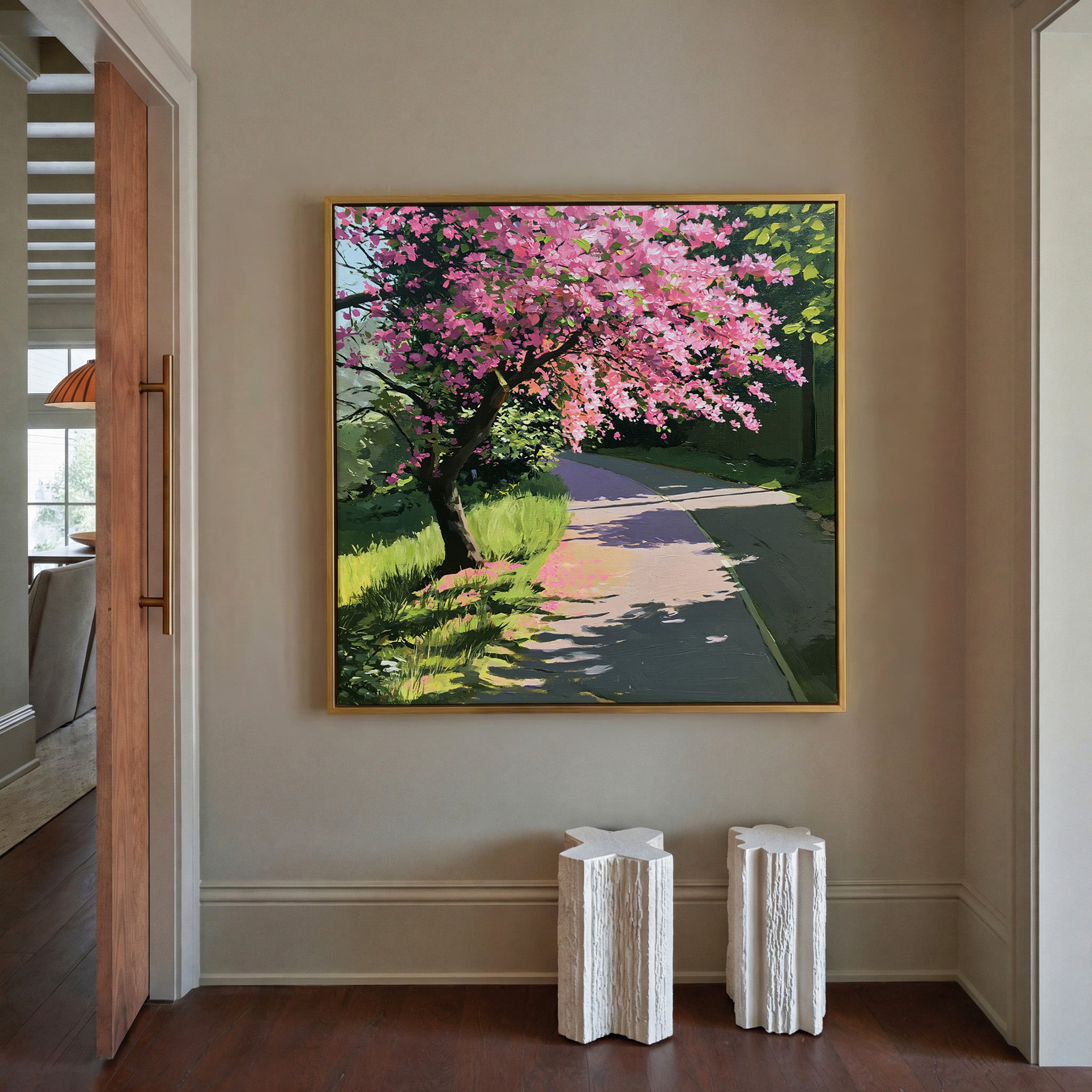 pink flowering tree beside a curving path canvas wall art in a gold frame in a styled room setting