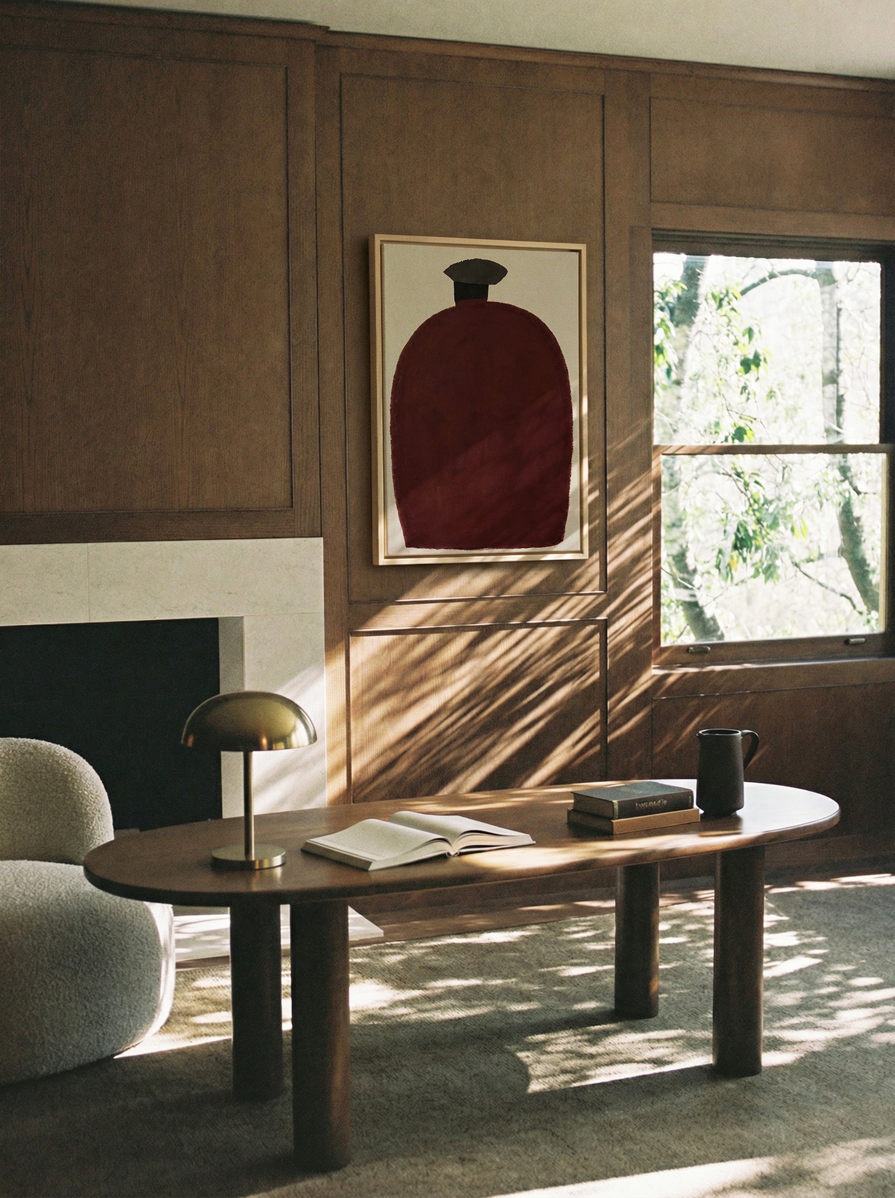 deep burgundy vessel shape with a dark cap on canvas wall art in a natural wood frame in a styled room setting