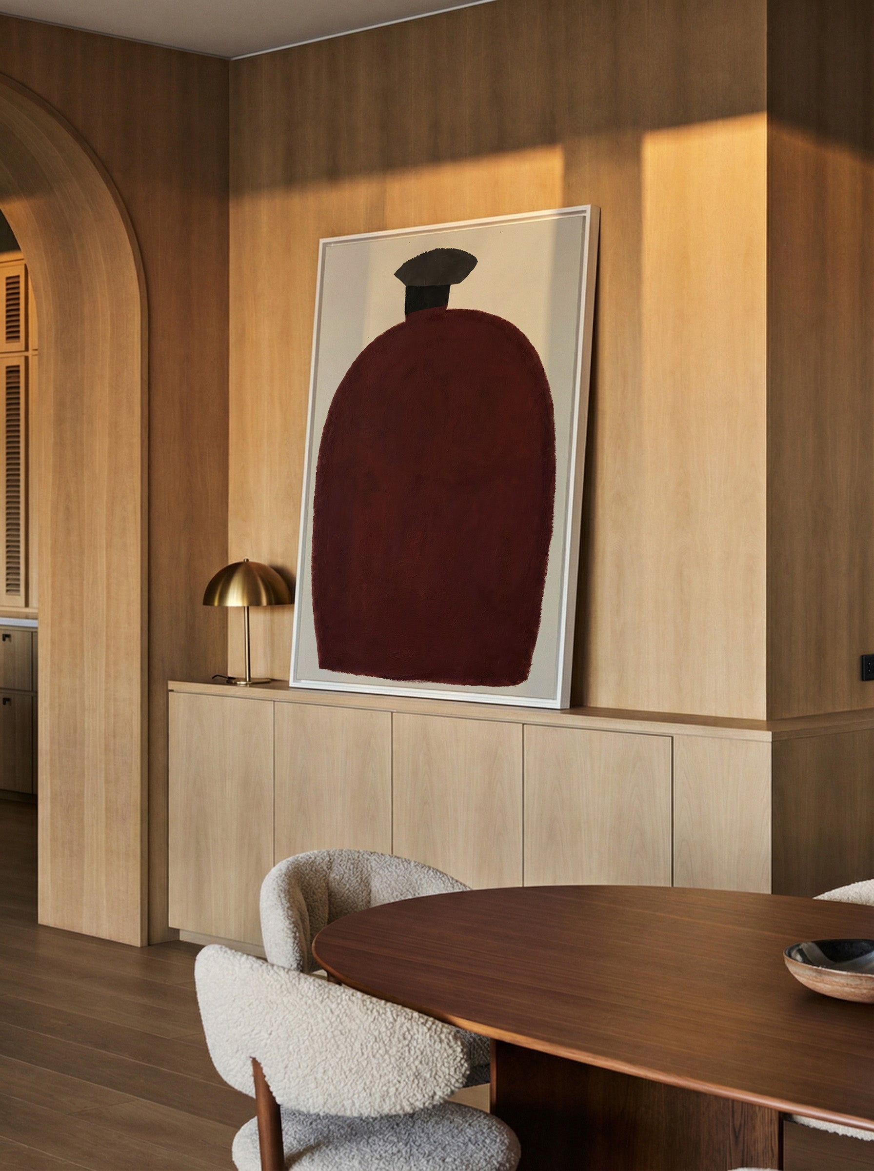 deep burgundy vessel shape with a dark cap on canvas wall art in a white frame in a styled room setting