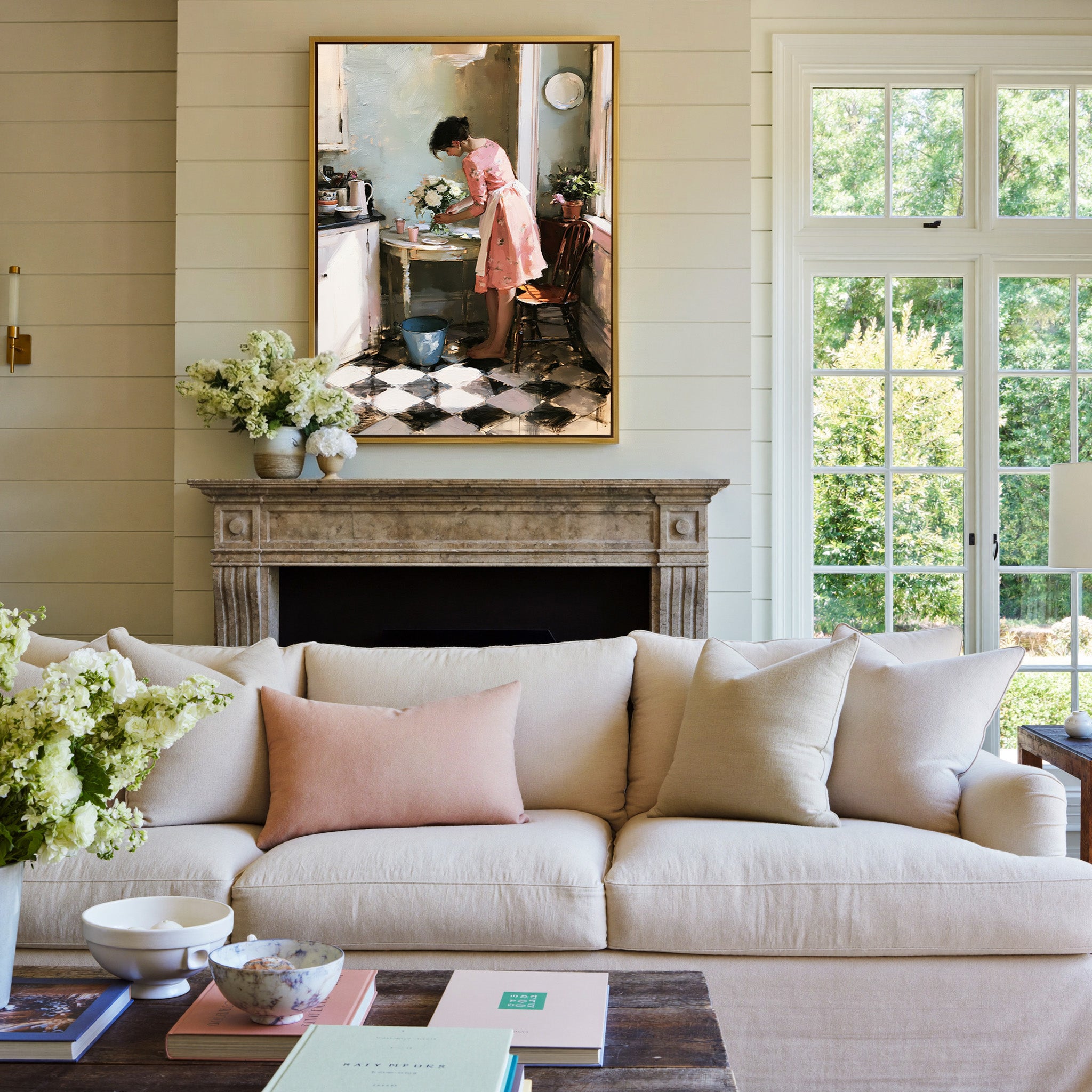 woman in a pink dress arranging white flowers canvas wall art in a gold frame above a mantel