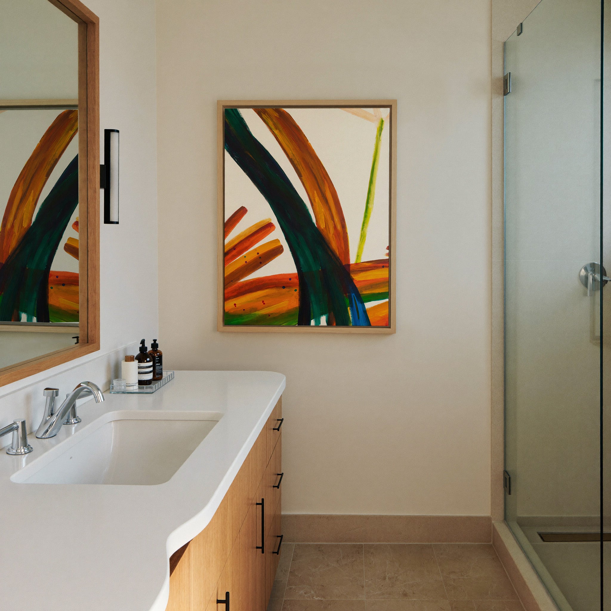 bold orange, green, and blue abstract with canvas wall art in a natural wood frame in a styled room setting
