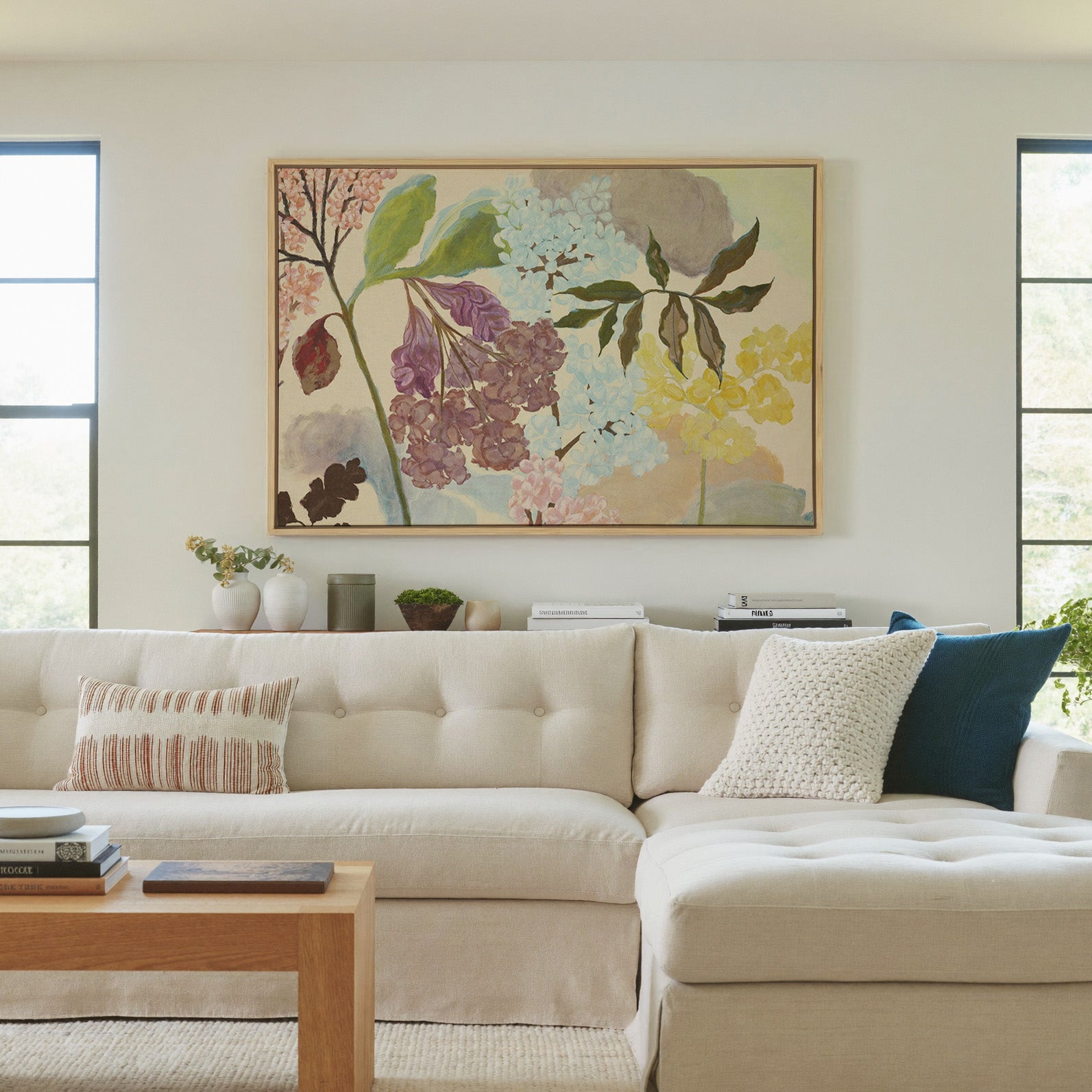 soft pastel floral branches with clustered canvas wall art in a natural wood frame in a living room
