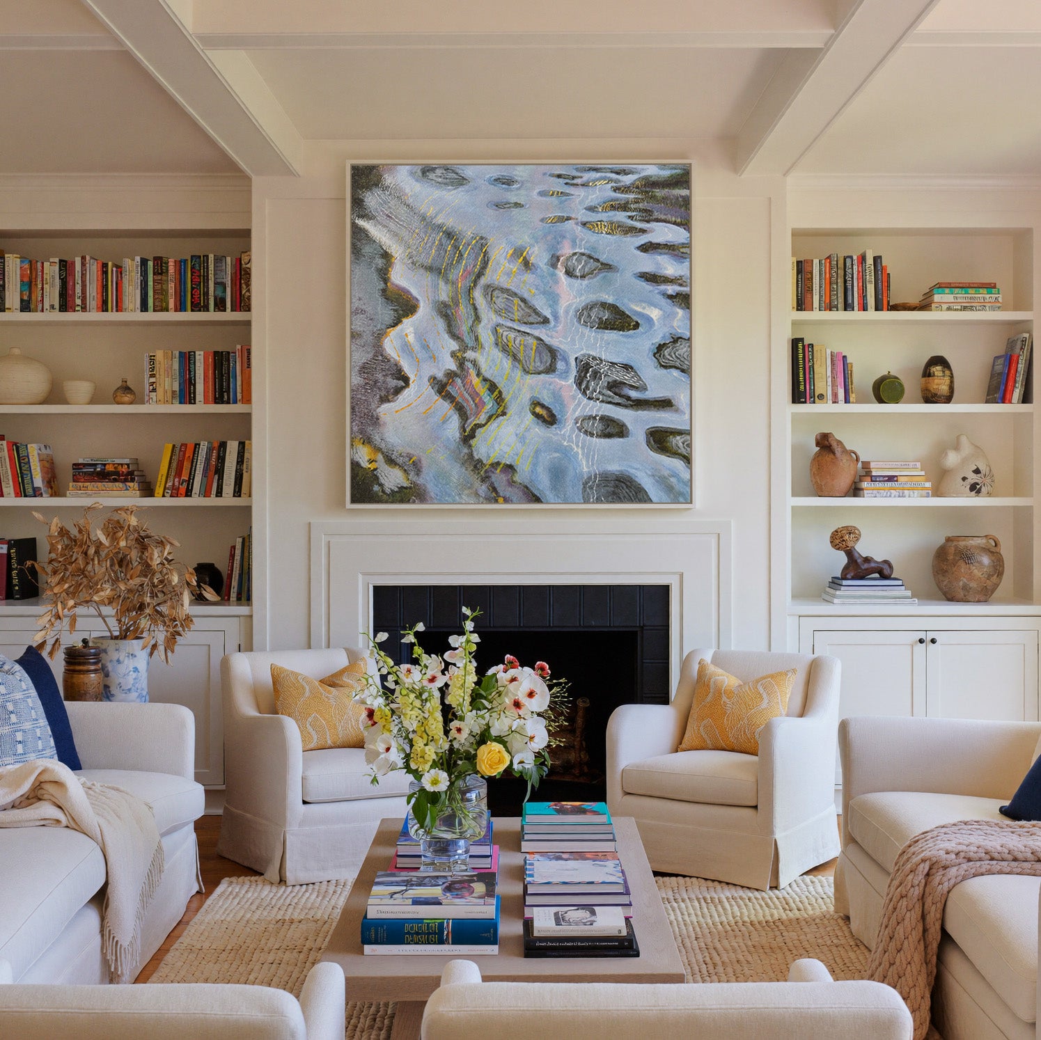 blue gray abstract with dark oval forms and canvas wall art in a white frame above a fireplace
