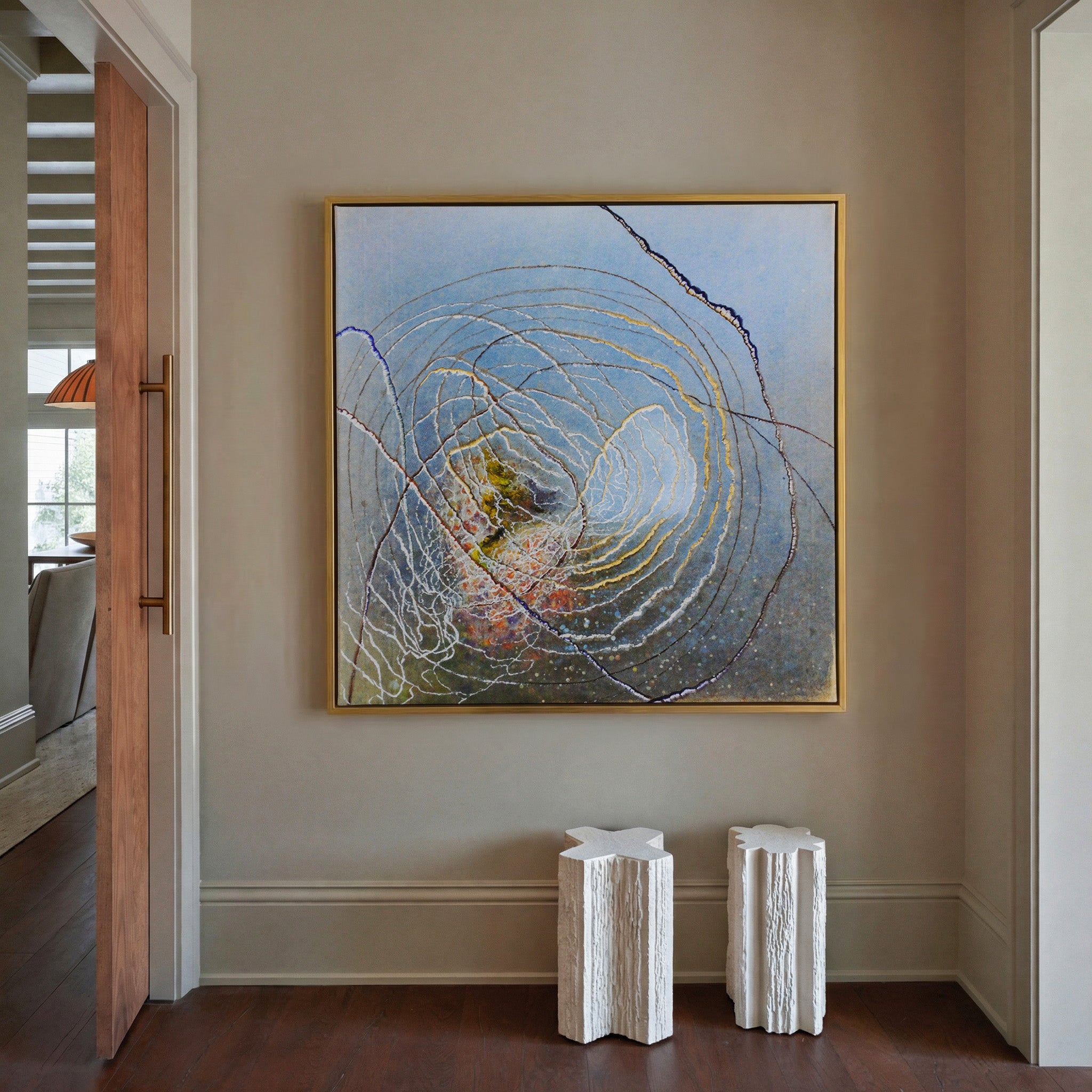 blue abstract with concentric rings and dark canvas wall art in a gold frame in a styled room setting