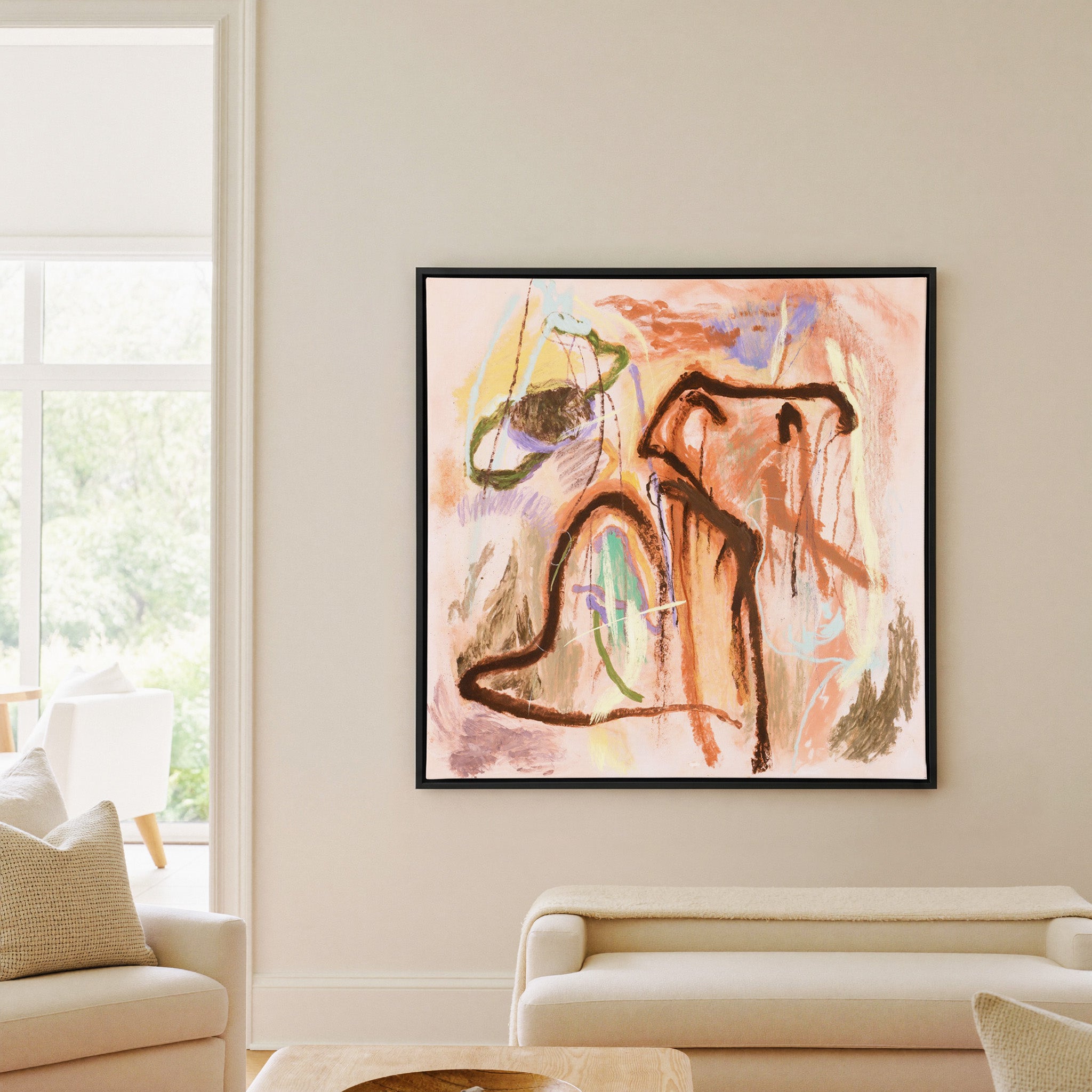 warm peach abstract with dark looping lines and canvas wall art in a black frame in a living room