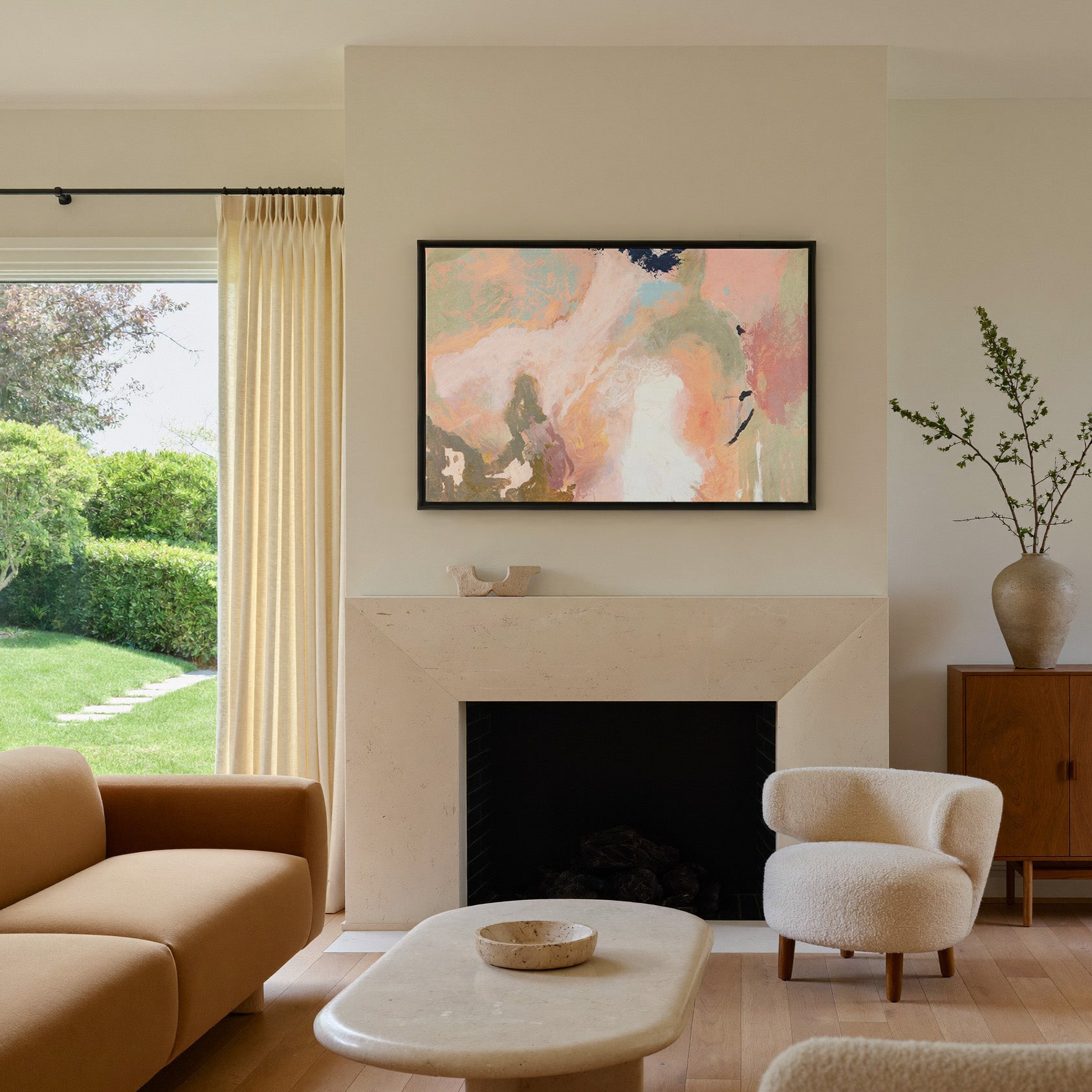 soft peach, sage, and cream abstract with dark canvas wall art in a black frame above a mantel
