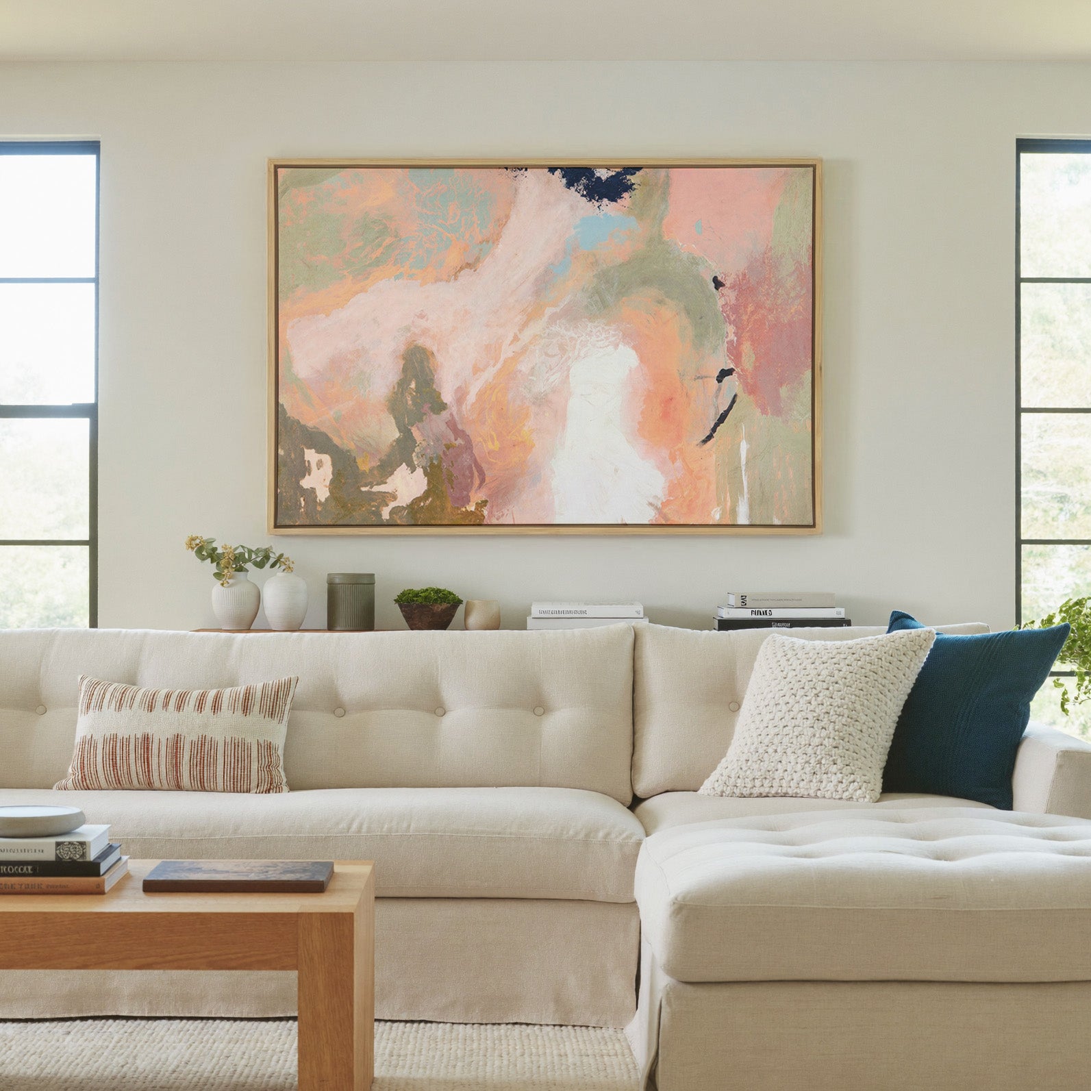 soft peach, sage, and cream abstract with dark canvas wall art in a natural wood frame in a living room