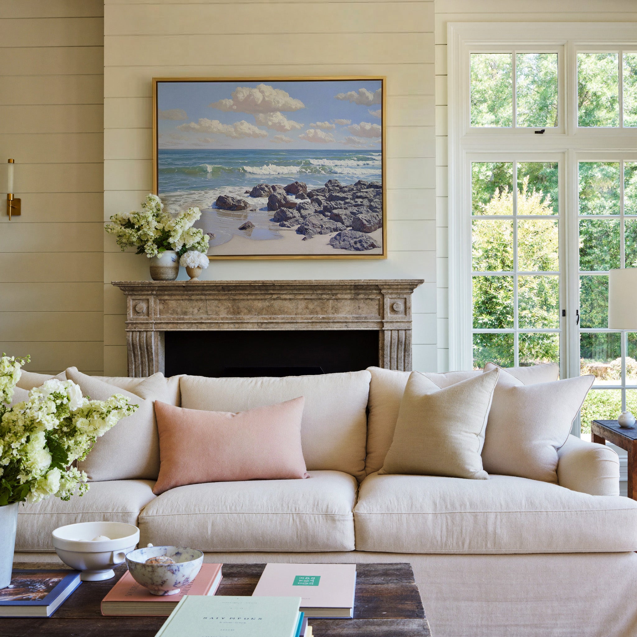 rocky shore with rolling surf and soft cloud canvas wall art in a gold frame above a mantel