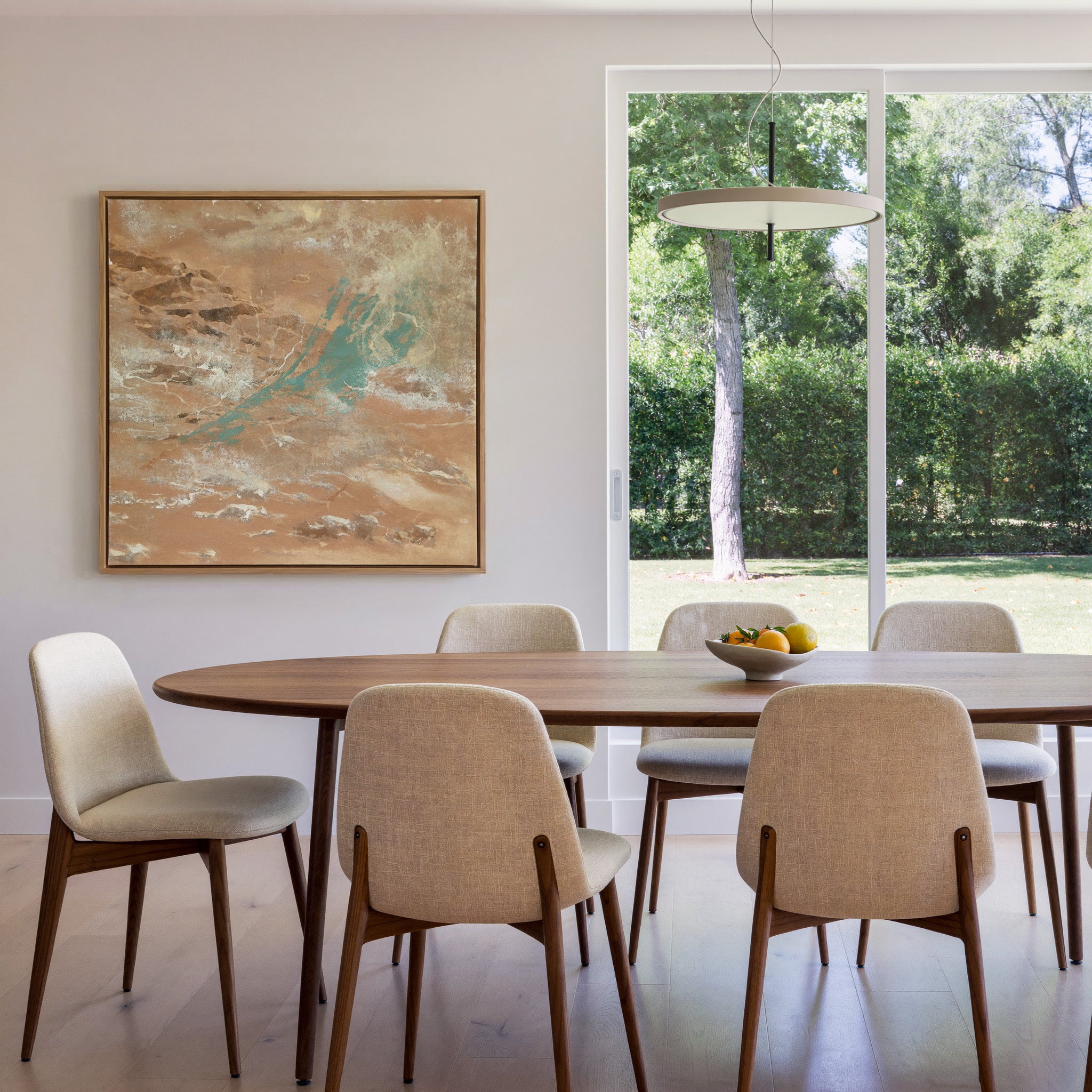 warm tan abstract with turquoise streaks and canvas wall art in an oak frame in a dining room