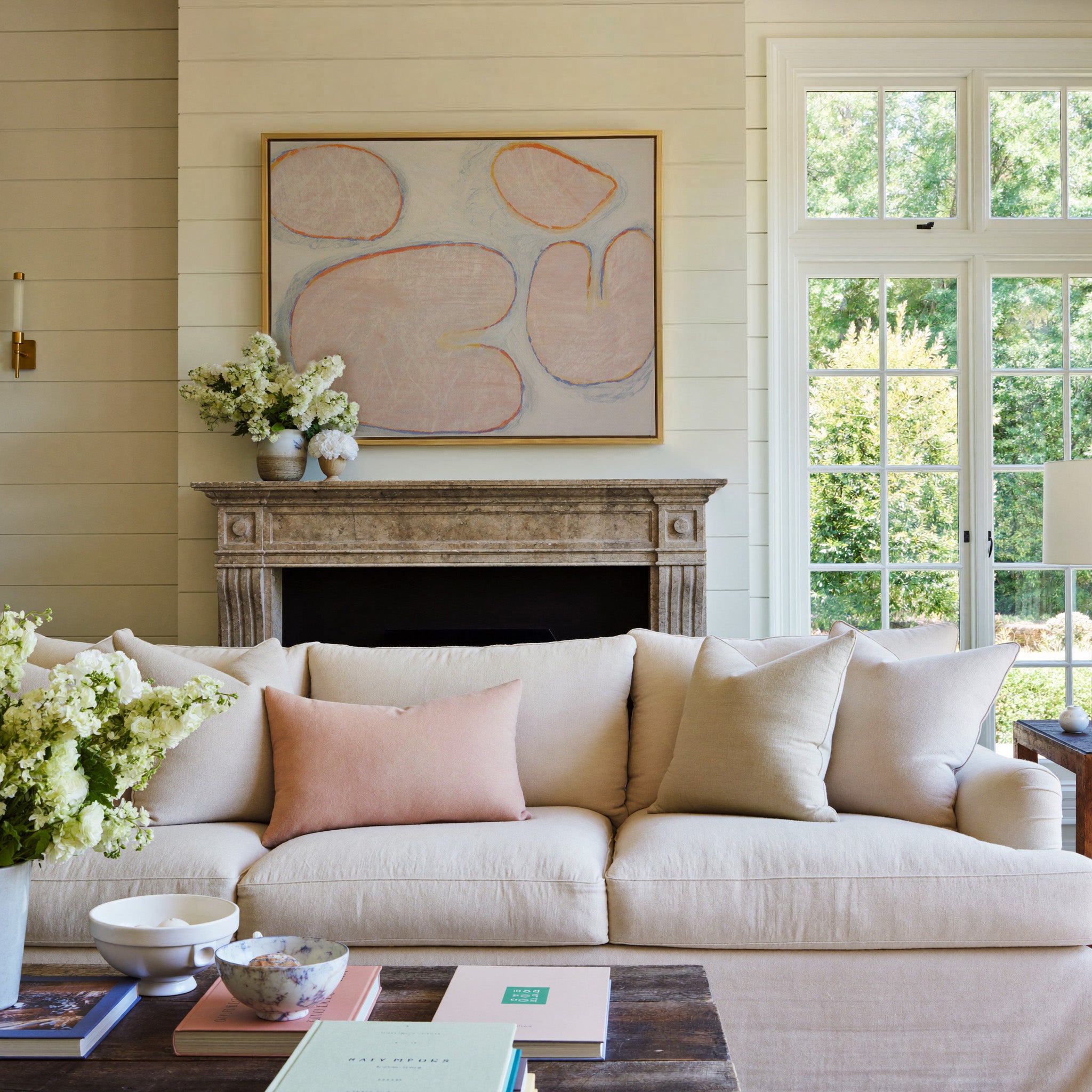 pale blush abstract with rounded forms and blue canvas wall art in a gold frame above a mantel
