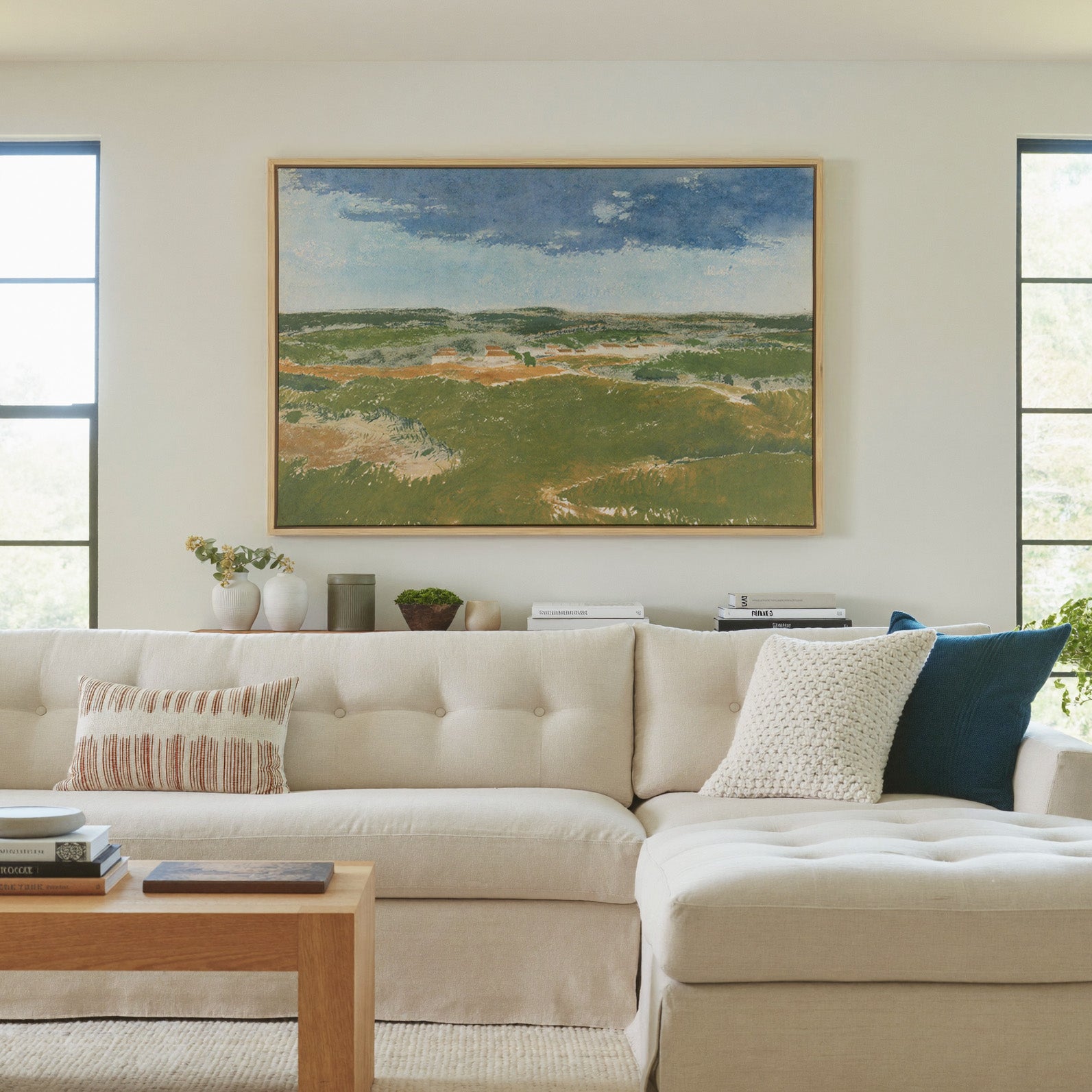 green dunes under a broad blue sky canvas wall art in a natural wood frame in a living room