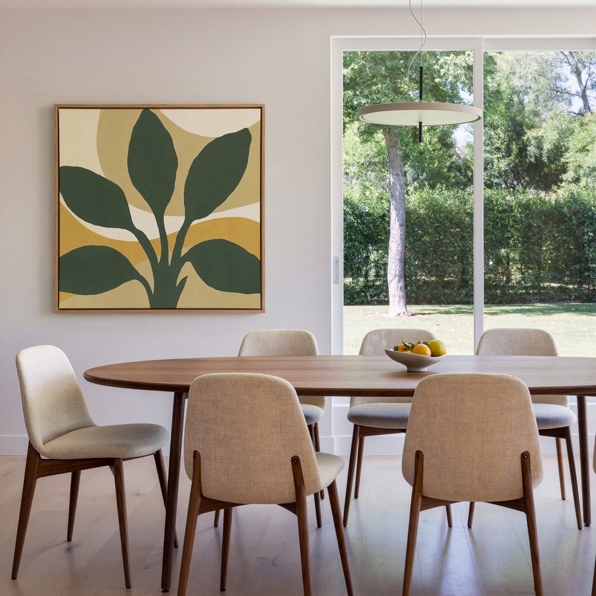 dark green leaf forms with warm ochre arcs canvas wall art in an oak frame in a dining room