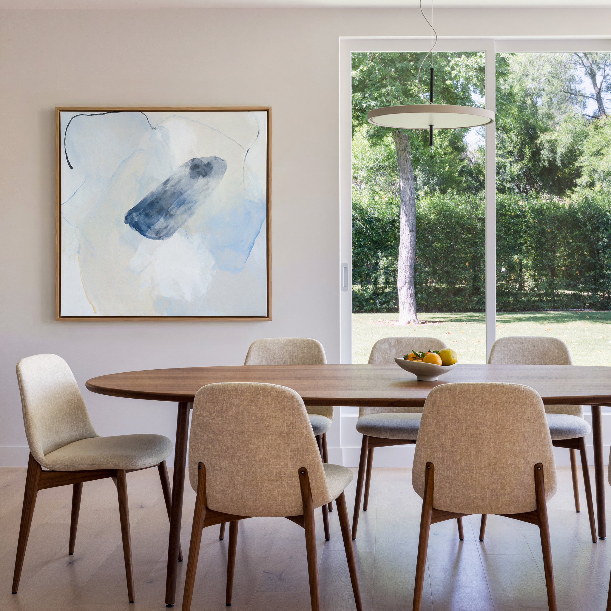 soft blue and ivory abstract with a dark indigo canvas wall art in an oak frame in a dining room