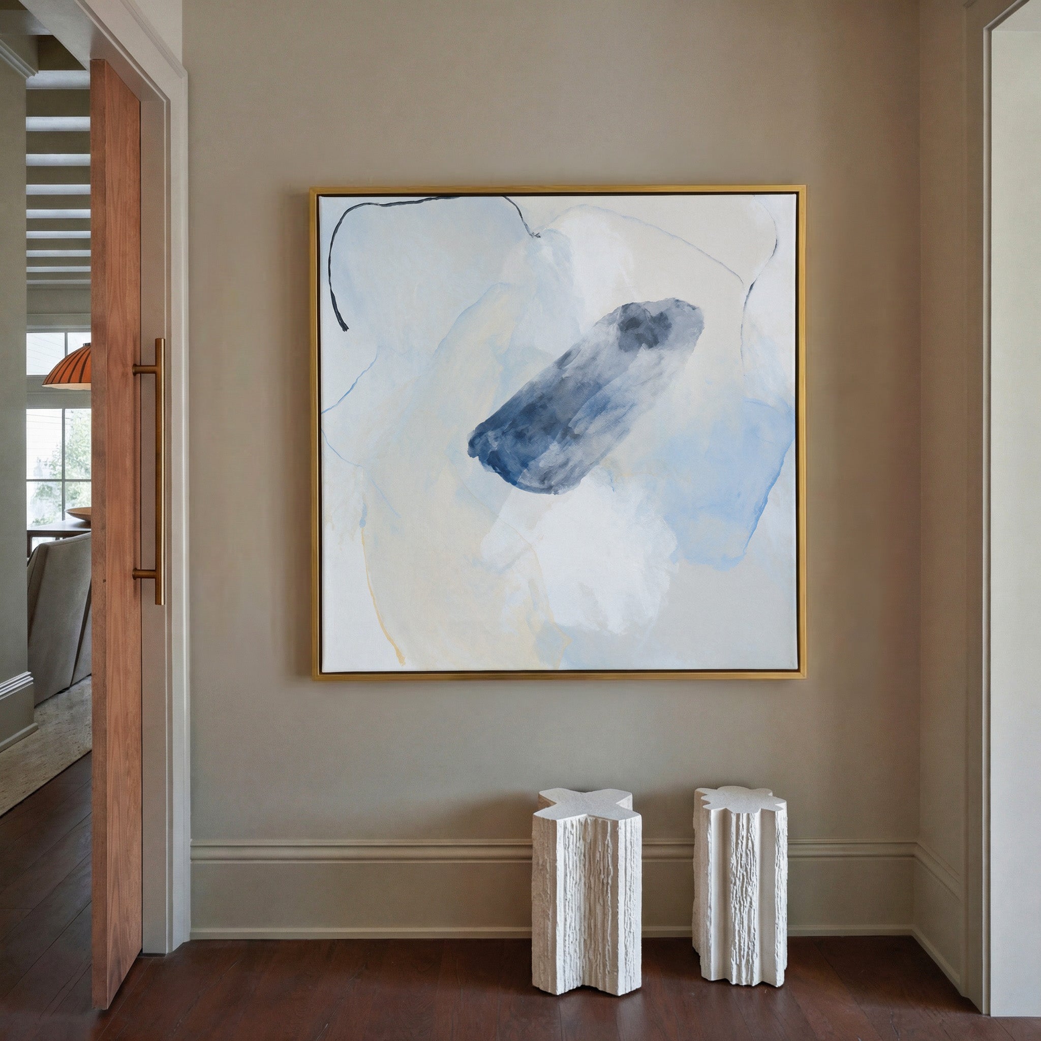 soft blue and ivory abstract with a dark indigo canvas wall art in a gold frame in a styled room setting