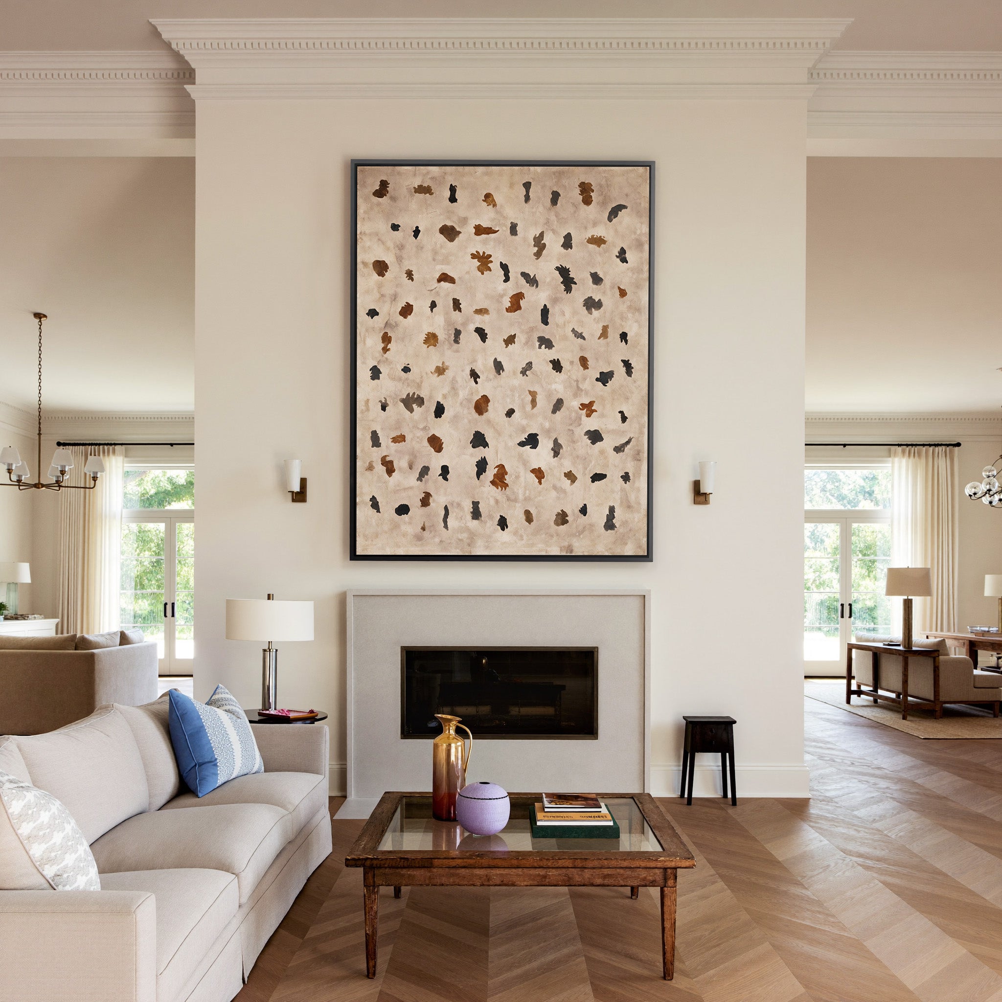 beige abstract with scattered black and rust canvas wall art in a black frame above a mantel