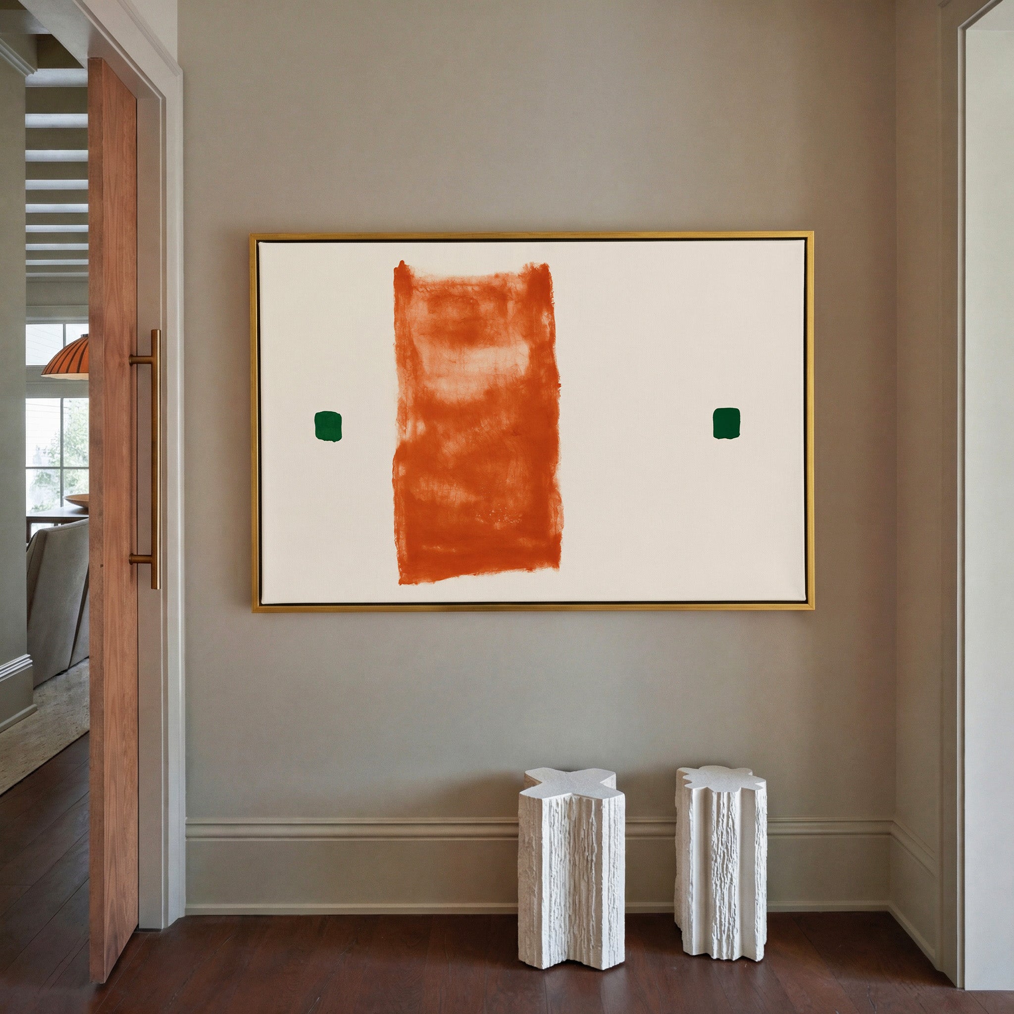 warm orange vertical block with two small green canvas wall art in a gold frame in a styled room setting