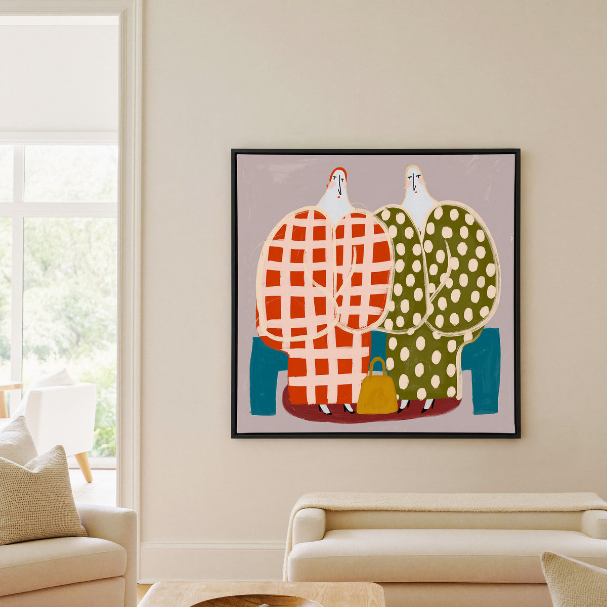 two stylized figures in check and polka dot canvas wall art in a black frame in a living room