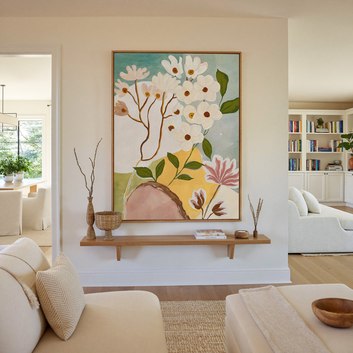 soft white blossoms with green leaves on a pale canvas wall art in an oak frame in a living room