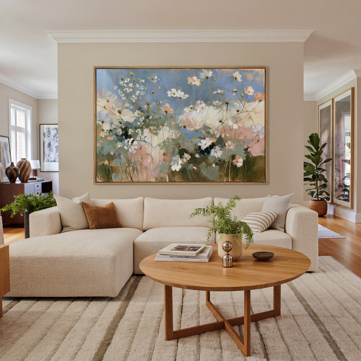 soft white and blush wildflowers under a blue canvas wall art in an oak frame in a living room