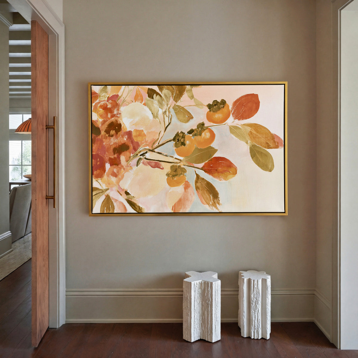 late autumn persimmon branches with orange canvas wall art in a gold frame in a styled room setting
