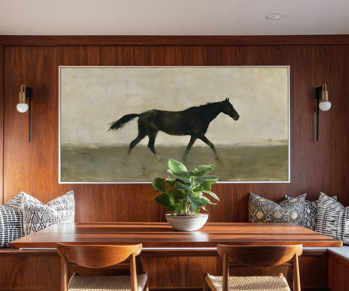 single dark horse in a pale open field canvas wall art in a white frame in a styled room setting