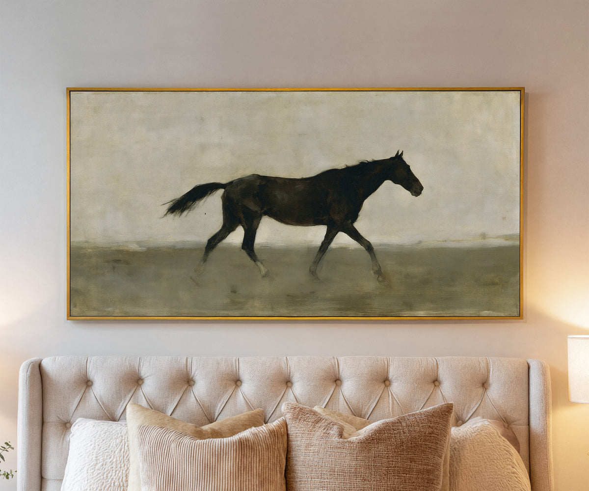 single dark horse in a pale open field canvas wall art in a gold frame above a bed