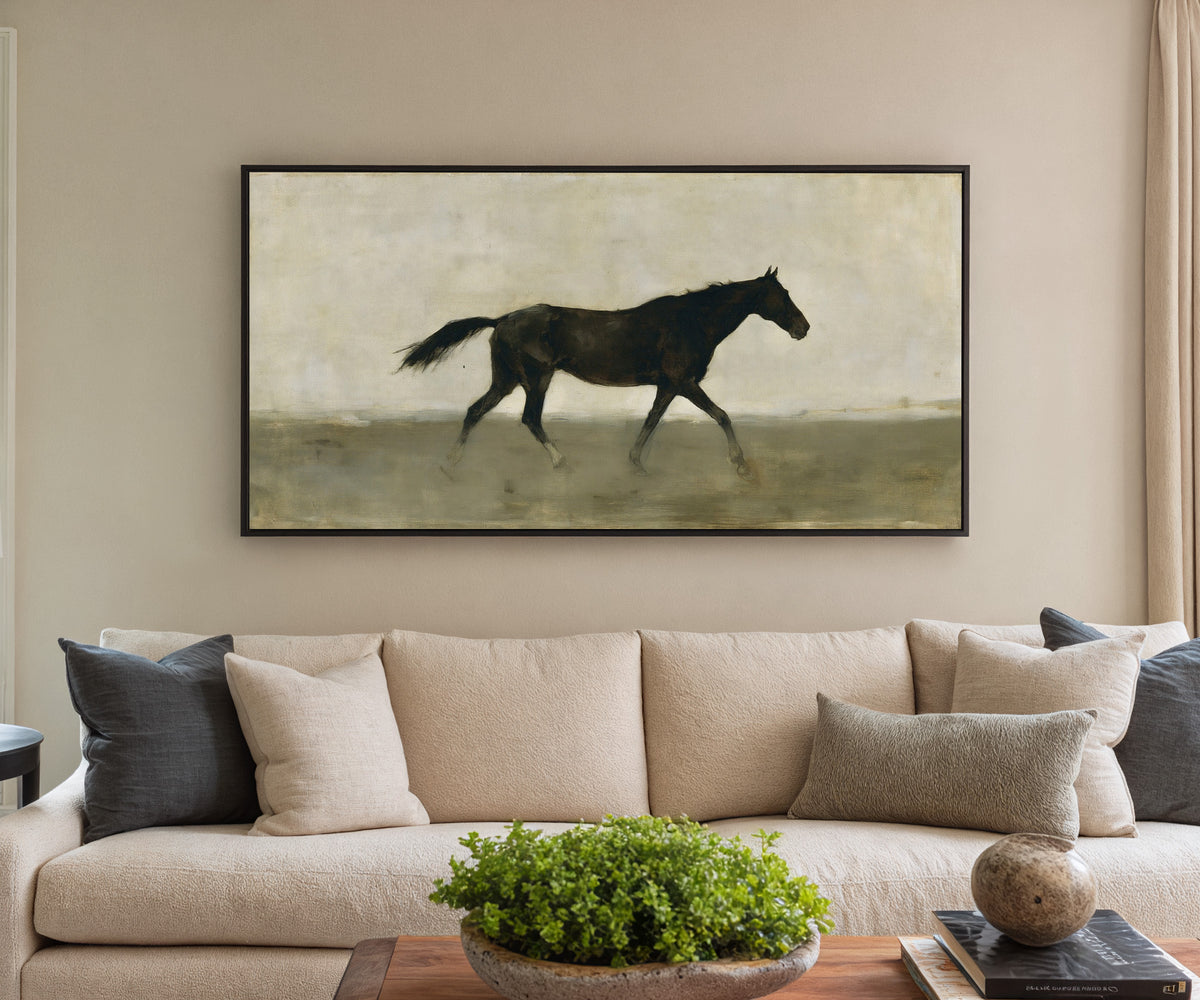 single dark horse in a pale open field canvas wall art in a black frame in a styled room setting