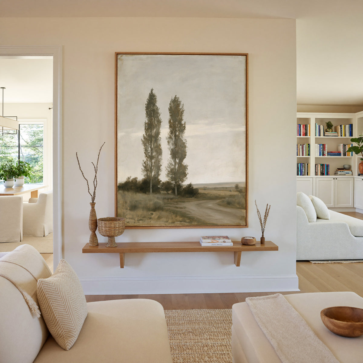 two slender poplar trees beside a curving dirt canvas wall art in an oak frame in a living room