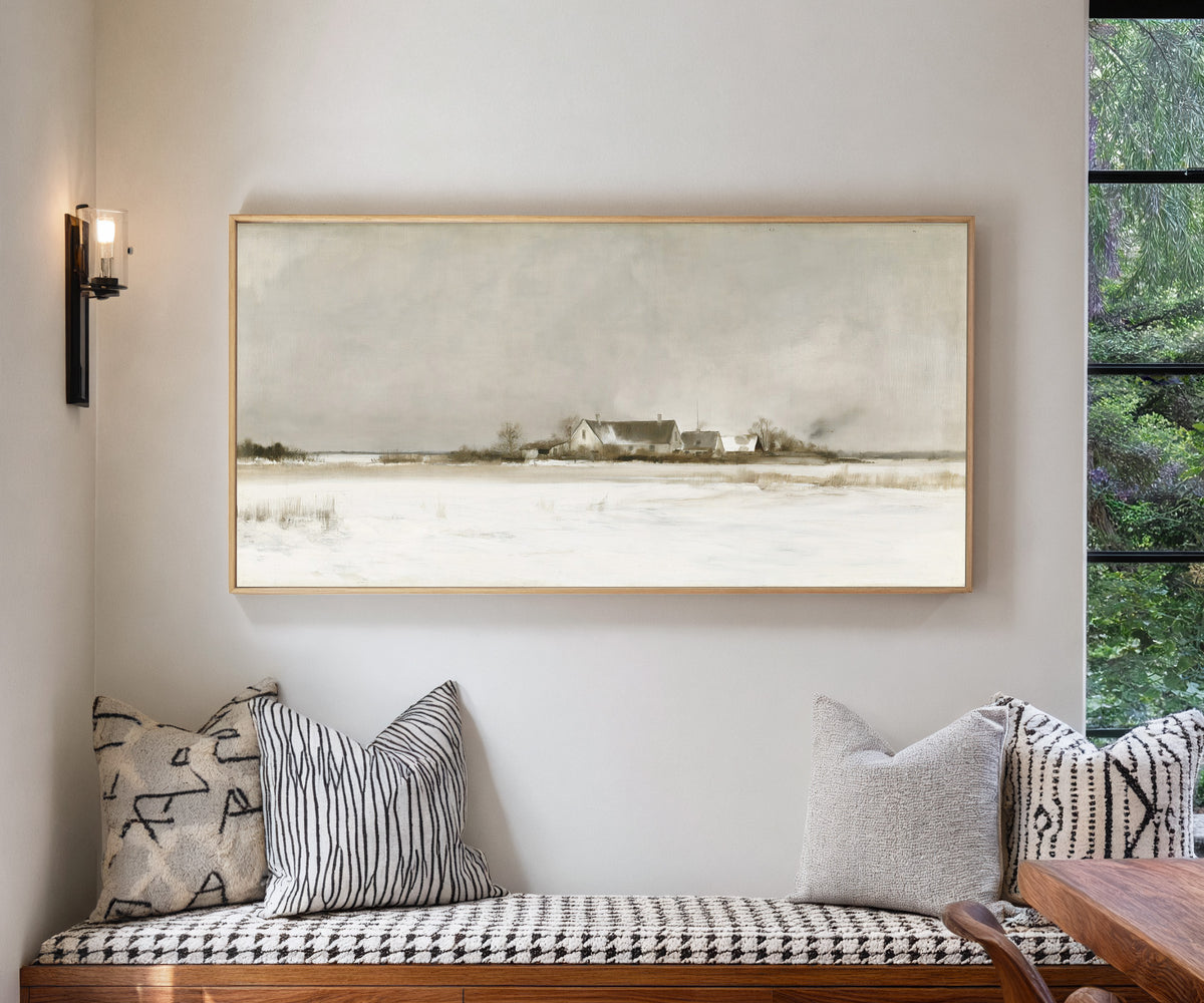 pale winter farmhouse landscape canvas wall art in a natural wood frame in a living room