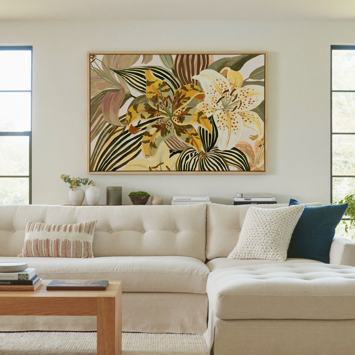 oversized yellow and cream tiger lilies among canvas wall art in a natural floater frame in a living room