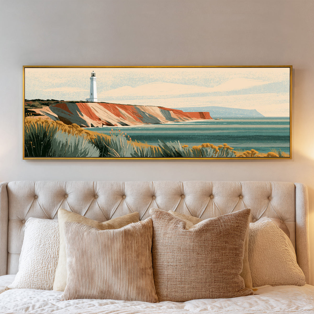 white lighthouse above terracotta cliffs and a canvas wall art in a gold floater frame above a bed