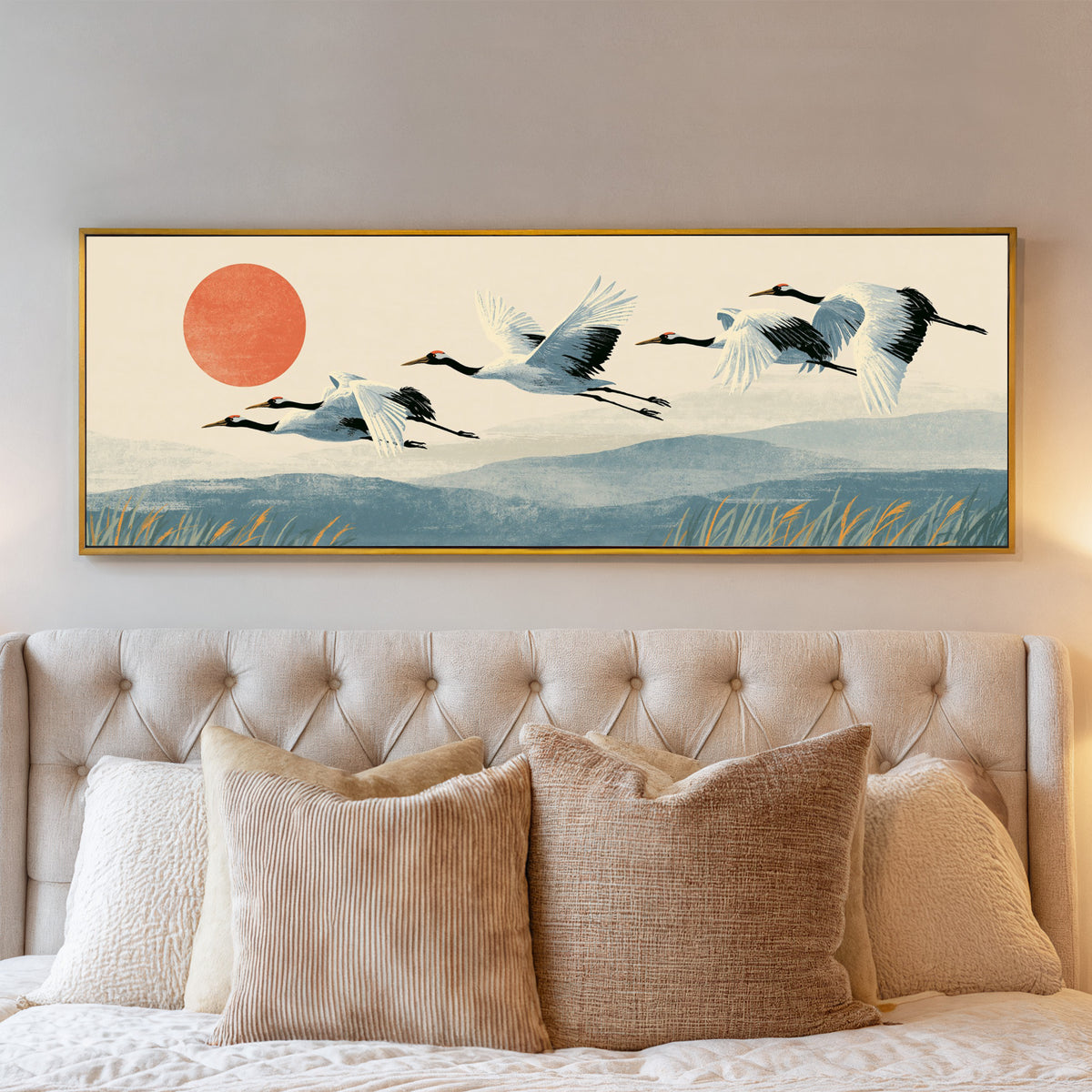 red crowned cranes flying over blue hills canvas wall art in a gold floater frame above a bed